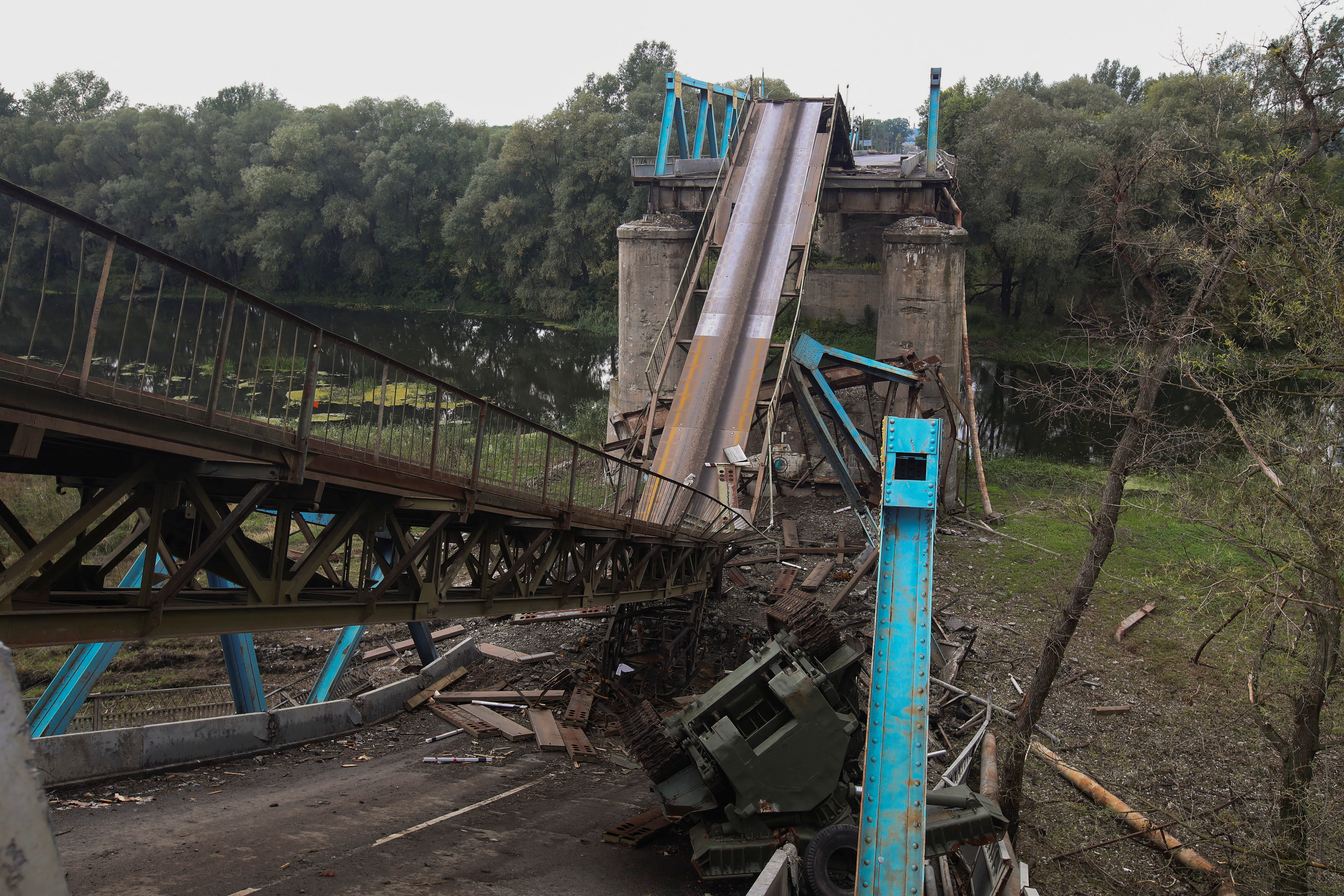 Military vehicle is seen near a destroyed bridge over the Siverskyi Donets river in the town of Izium