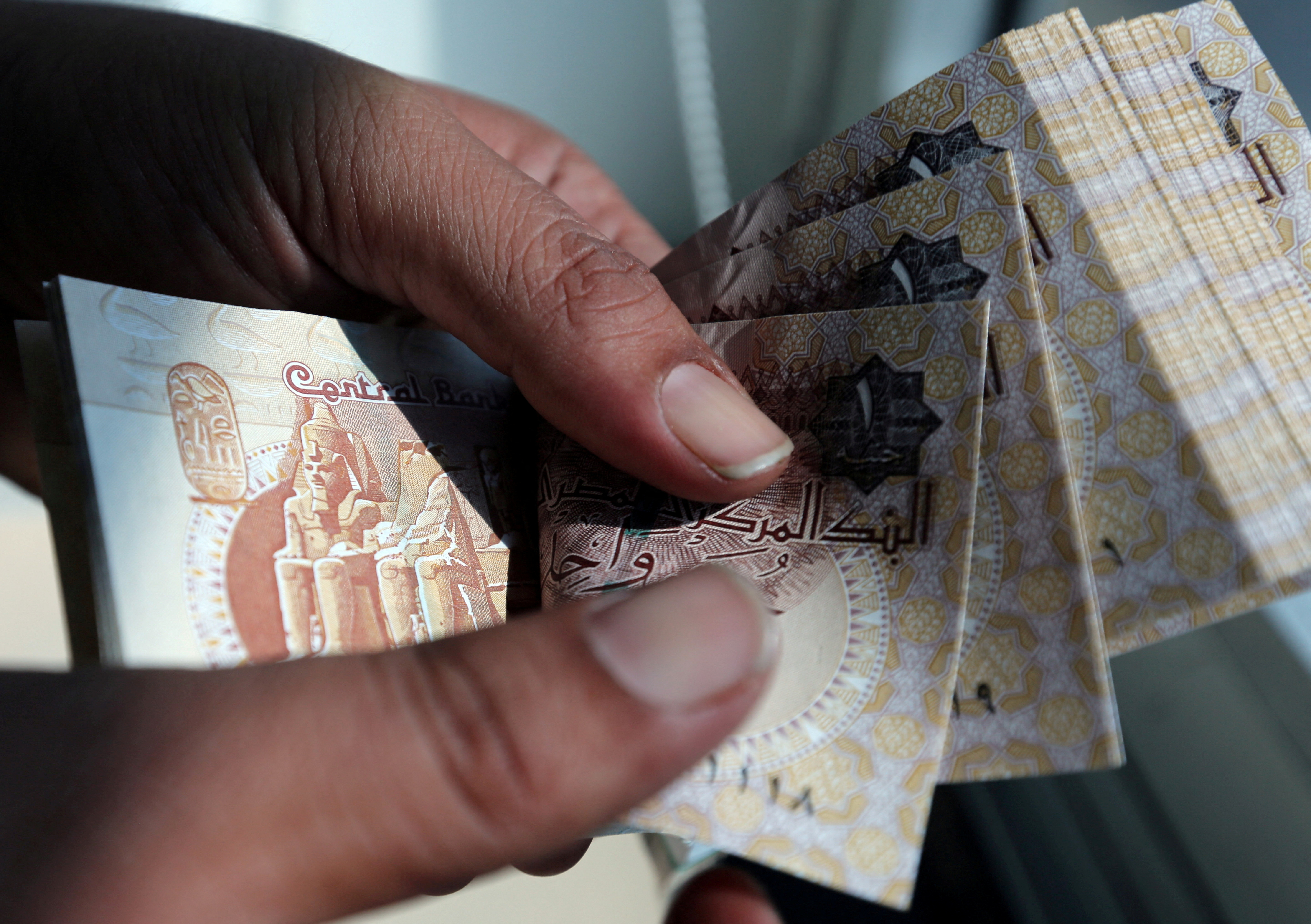 A man counts Egyptian pounds outside a bank in Cairo
