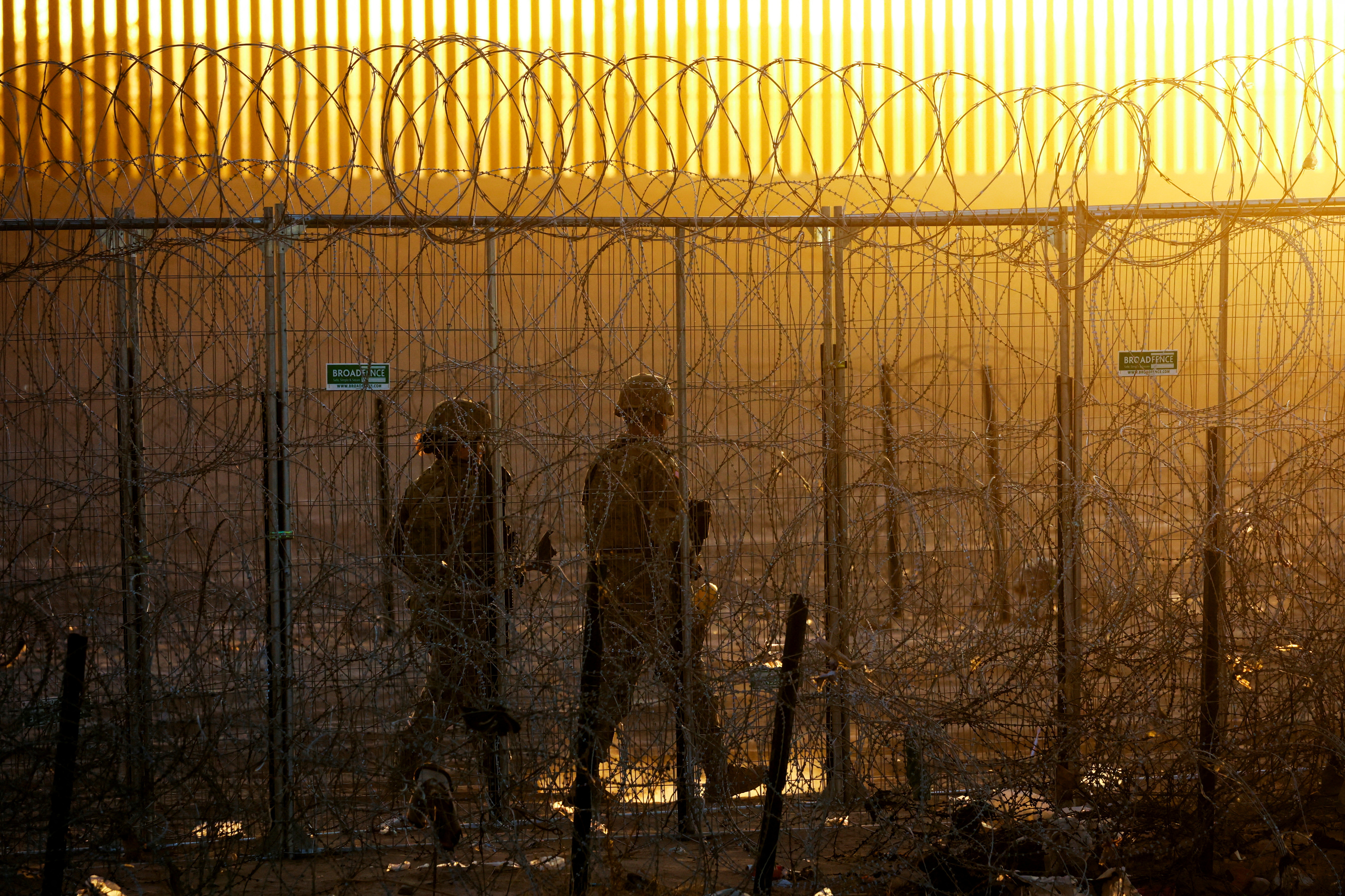 Members of the Texas National Guard stand guard near a razor wire fence to inhibit the crossing of migrants into the United States, seen from Ciudad Juarez