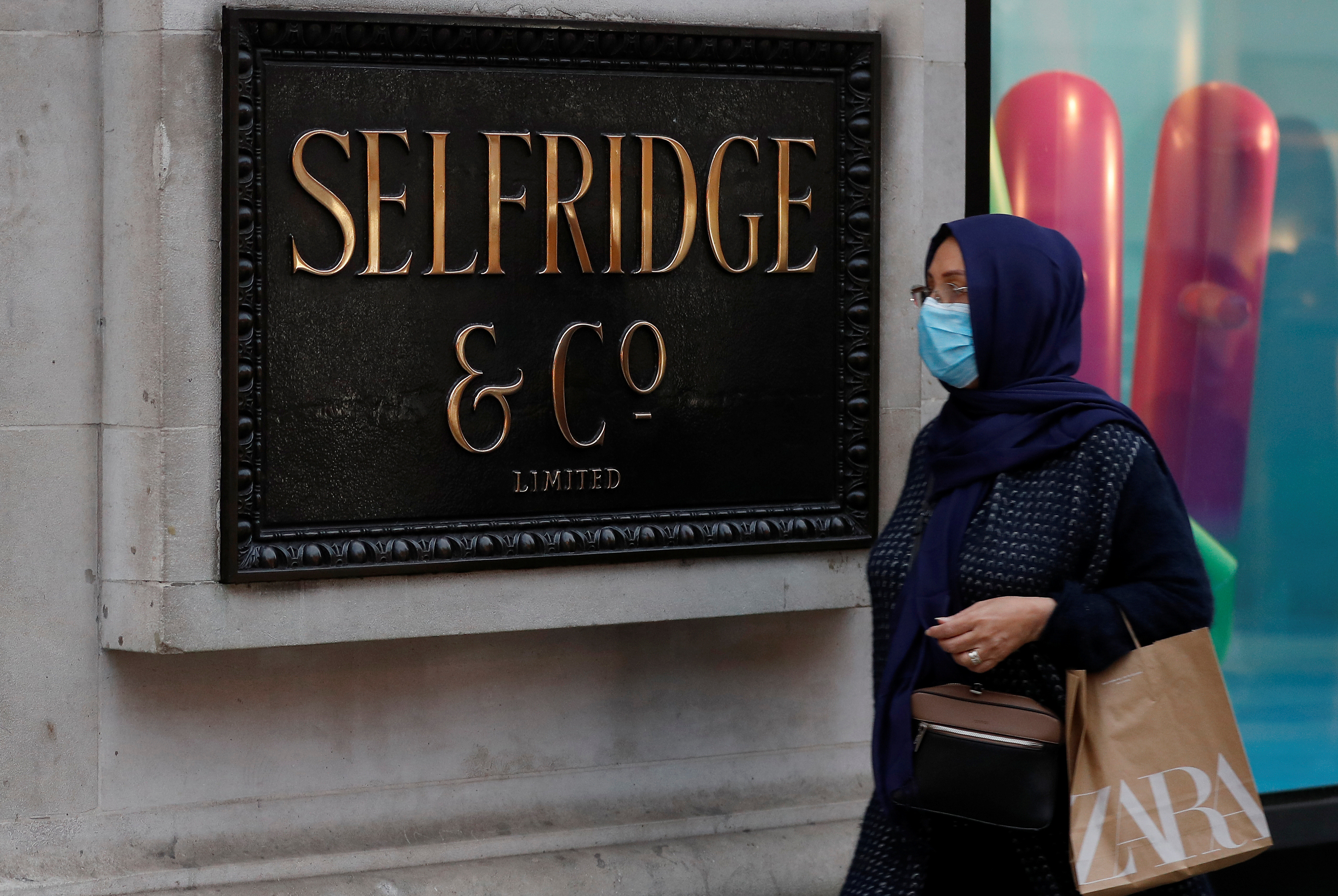 A woman wearing a face mask walks past the Selfridges Oxford street store prior to the company's temporary closure of its UK branches, in London