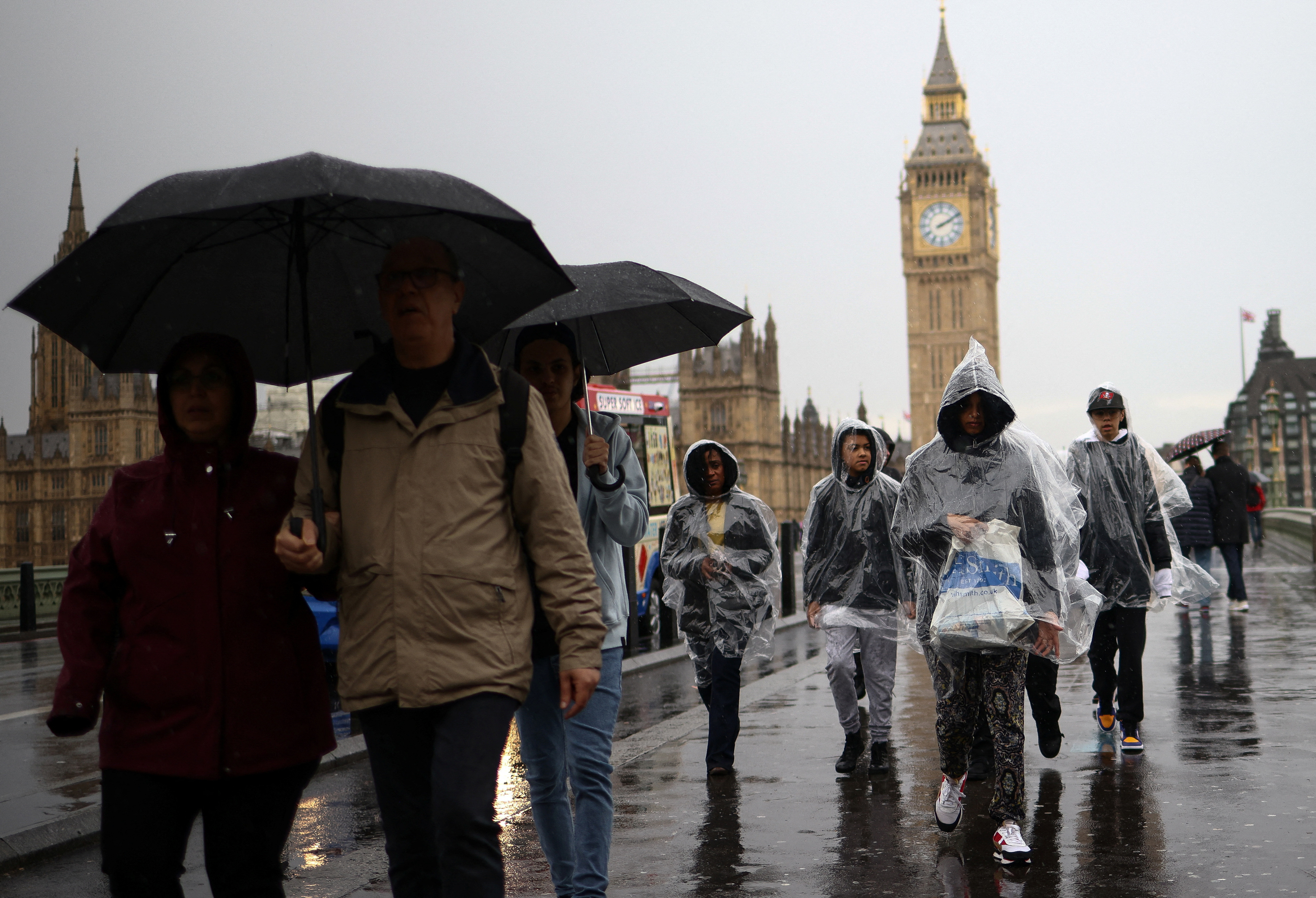 People walk over Westminster Bridge during heavy rainfall in London