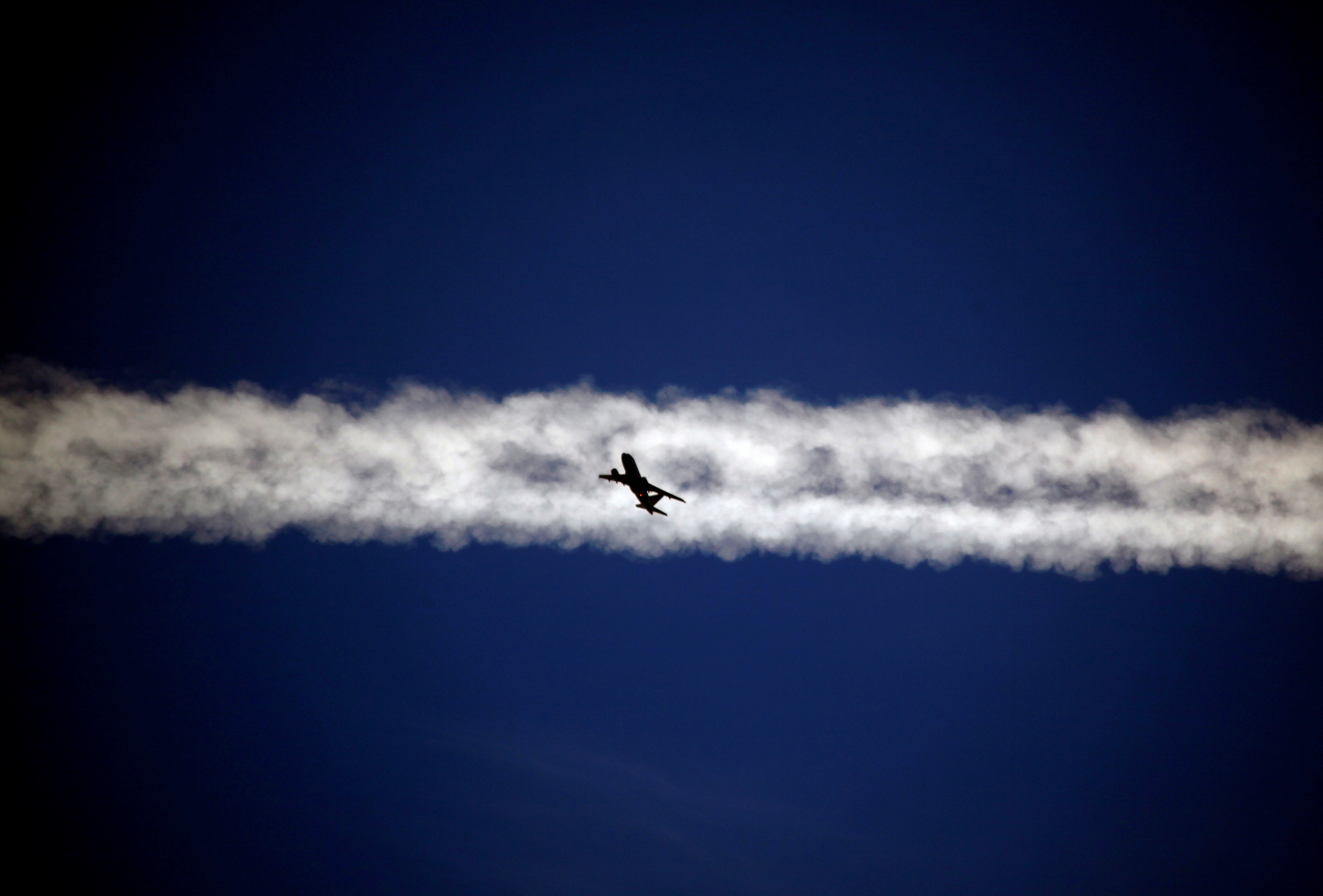 An aeroplane flies underneath the jet stream of another aircraft above the Italian city of Padova