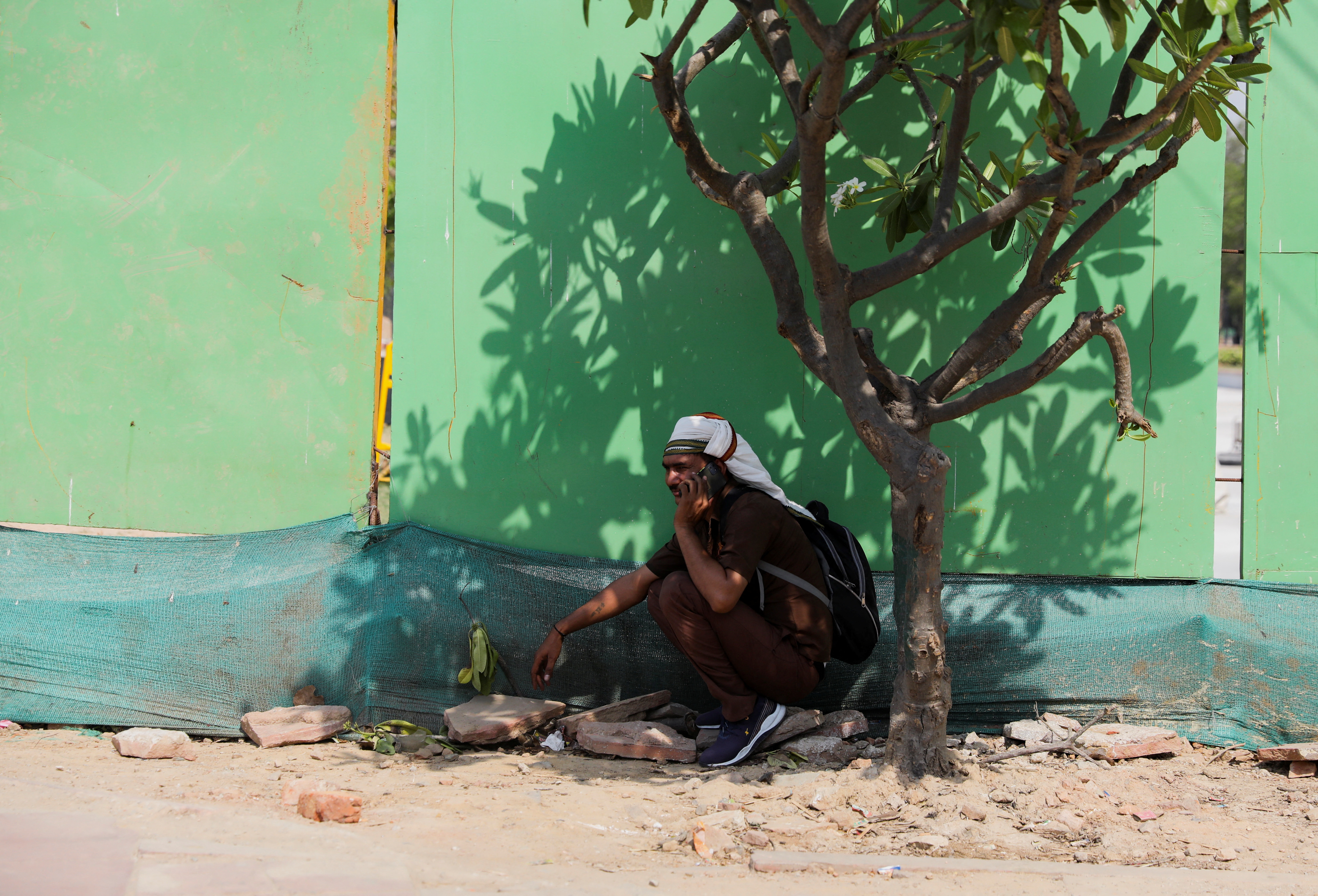 A man takes shelter under a tree on a hot summer day, in New Delhi