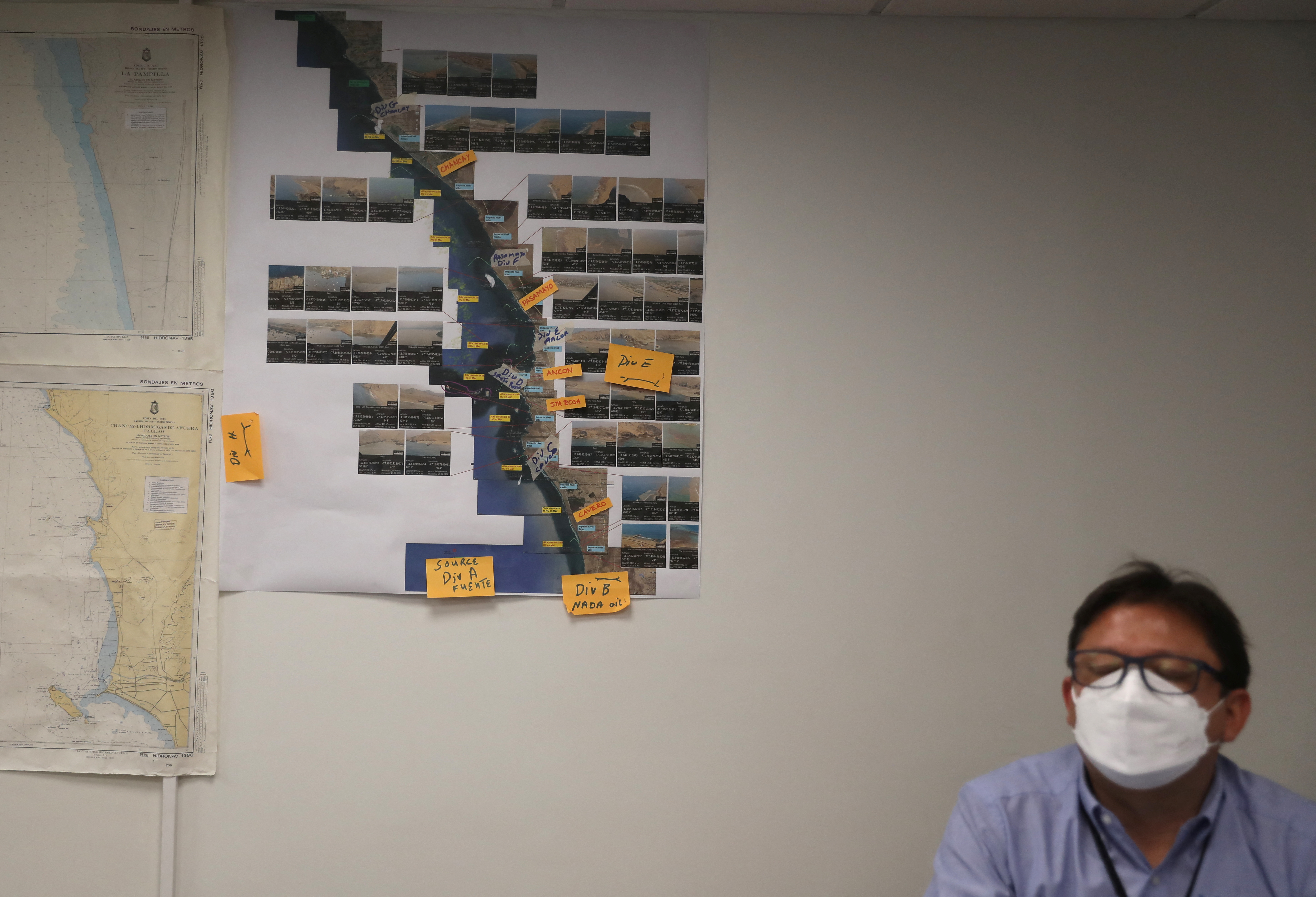 A Repsol worker sits next to pictures showing areas affected by oil spill, at the La Pampilla refinery in Ventanilla