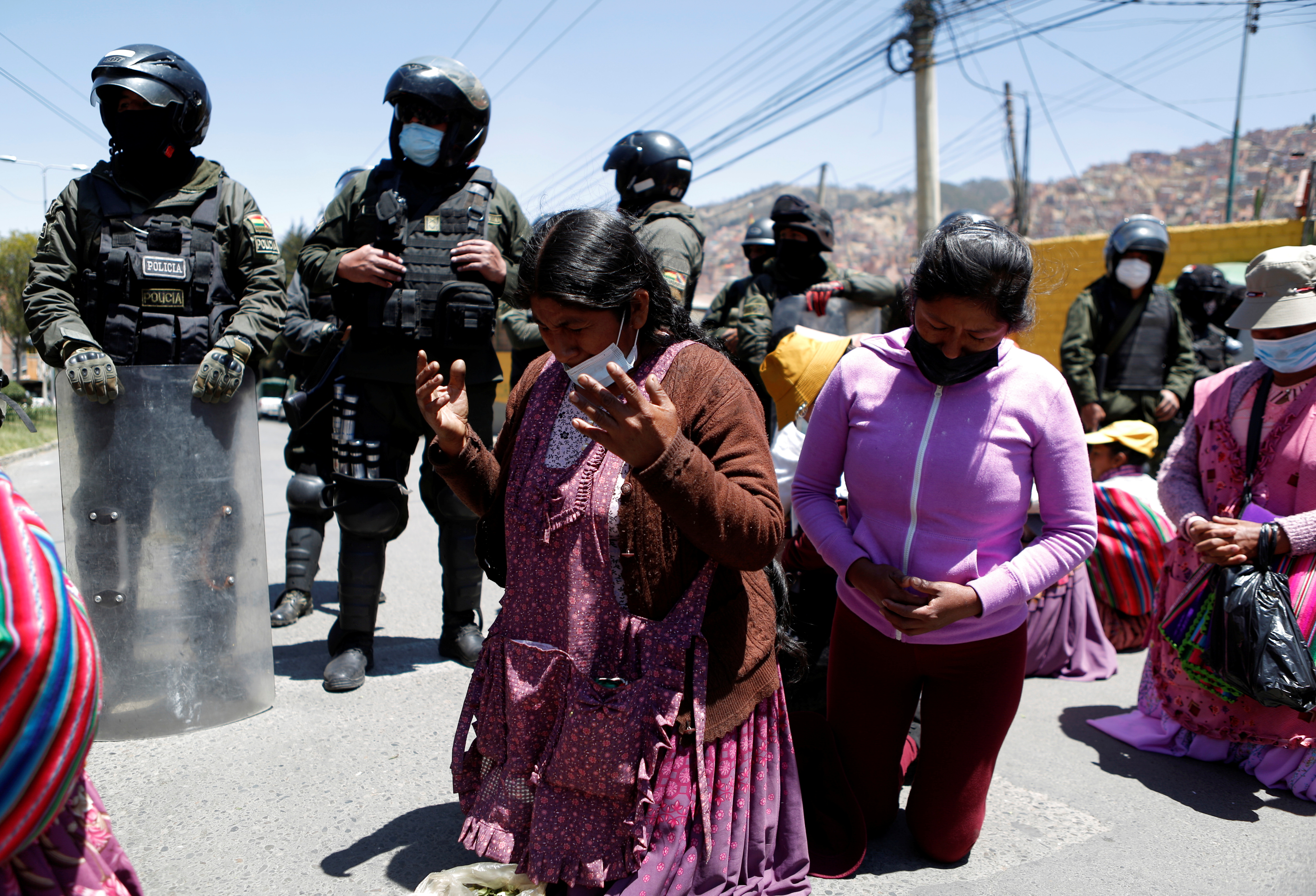 Coca growers from the Yungas region pray in front of police during a protest over the control of the leaf's main market, in La Paz, Bolivia, September 28, 2021. REUTERS/Manuel Claure