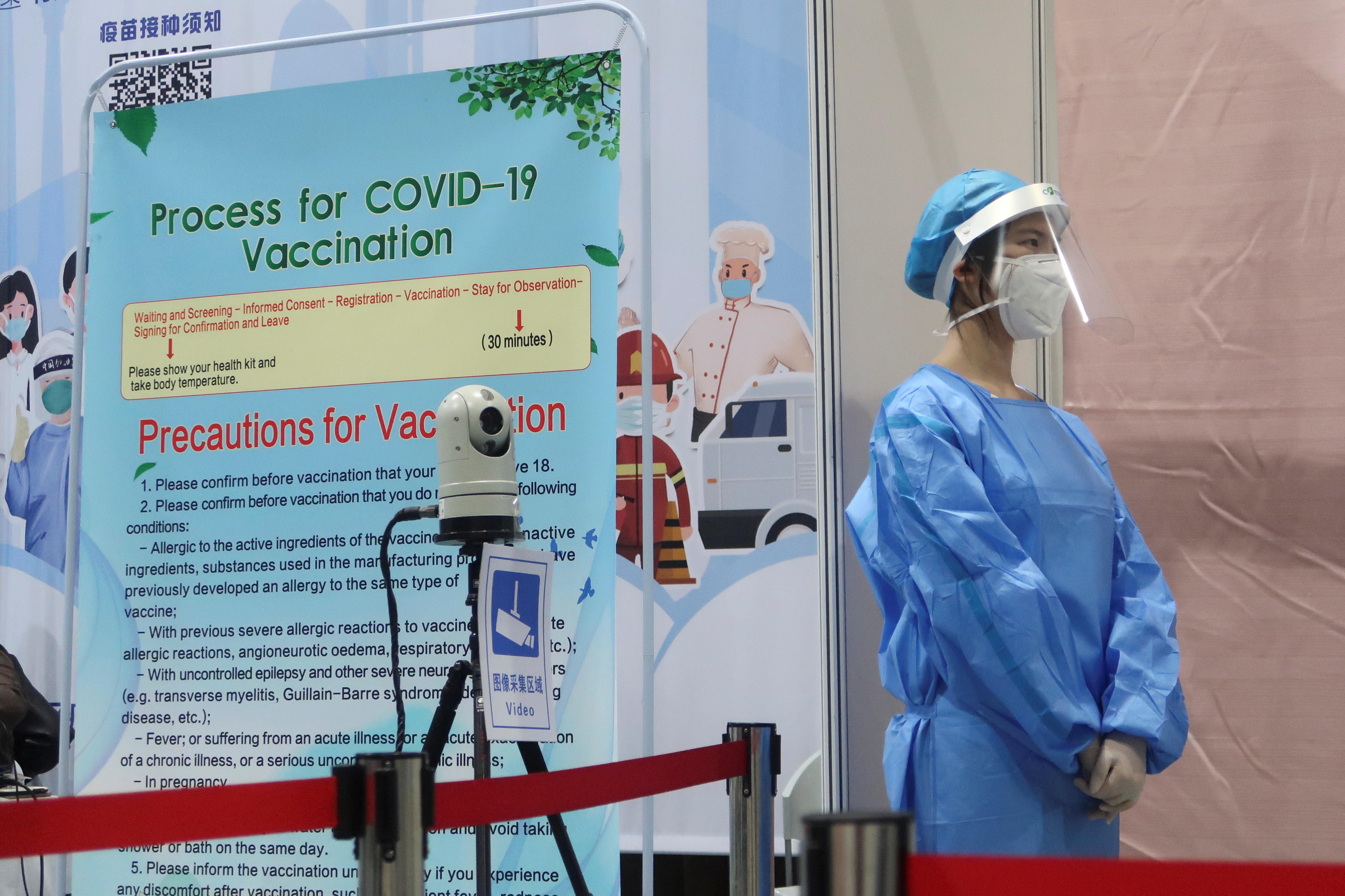 A staff member waits outside a booth where people receive a vaccine against the coronavirus disease (COVID-19) at a vaccination center in Beijing