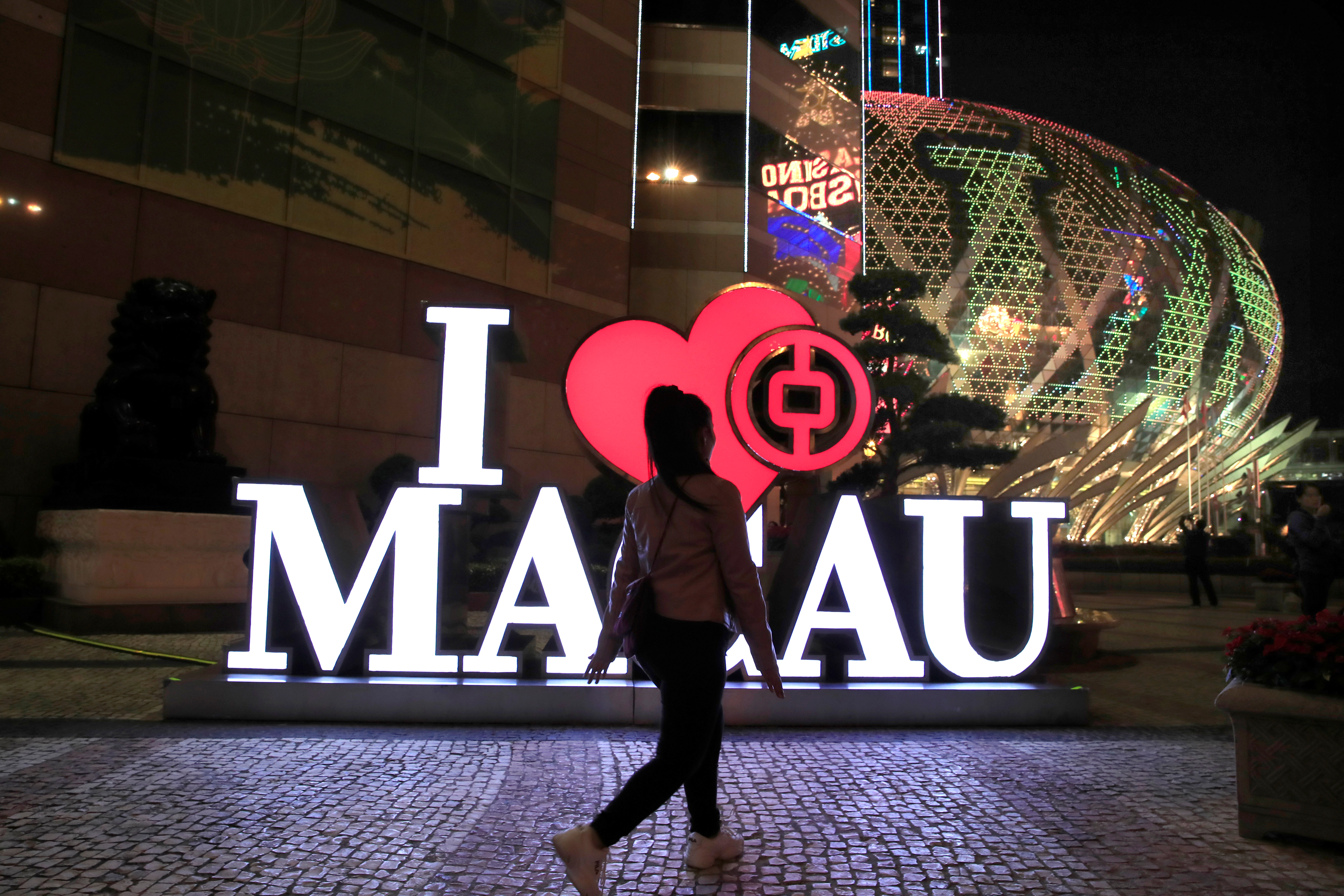 A woman walks past a Bank of China branch next to the Grand Lisboa hotel and casino (R) in Macau, China December 21, 2019. REUTERS/Jason Lee  