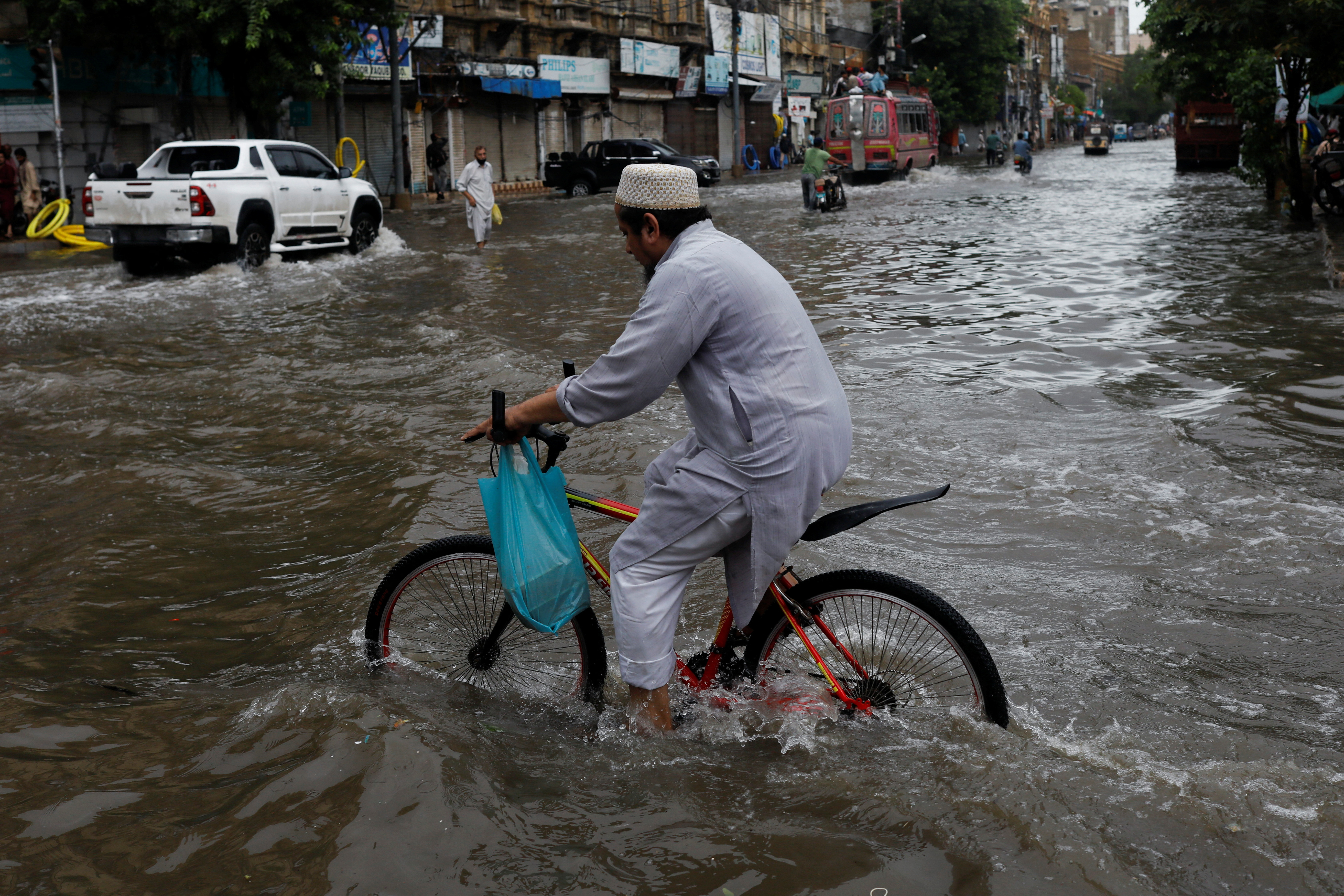 A man rides bicycle along a flooded road, following heavy rains during the monsoon season in Karachi