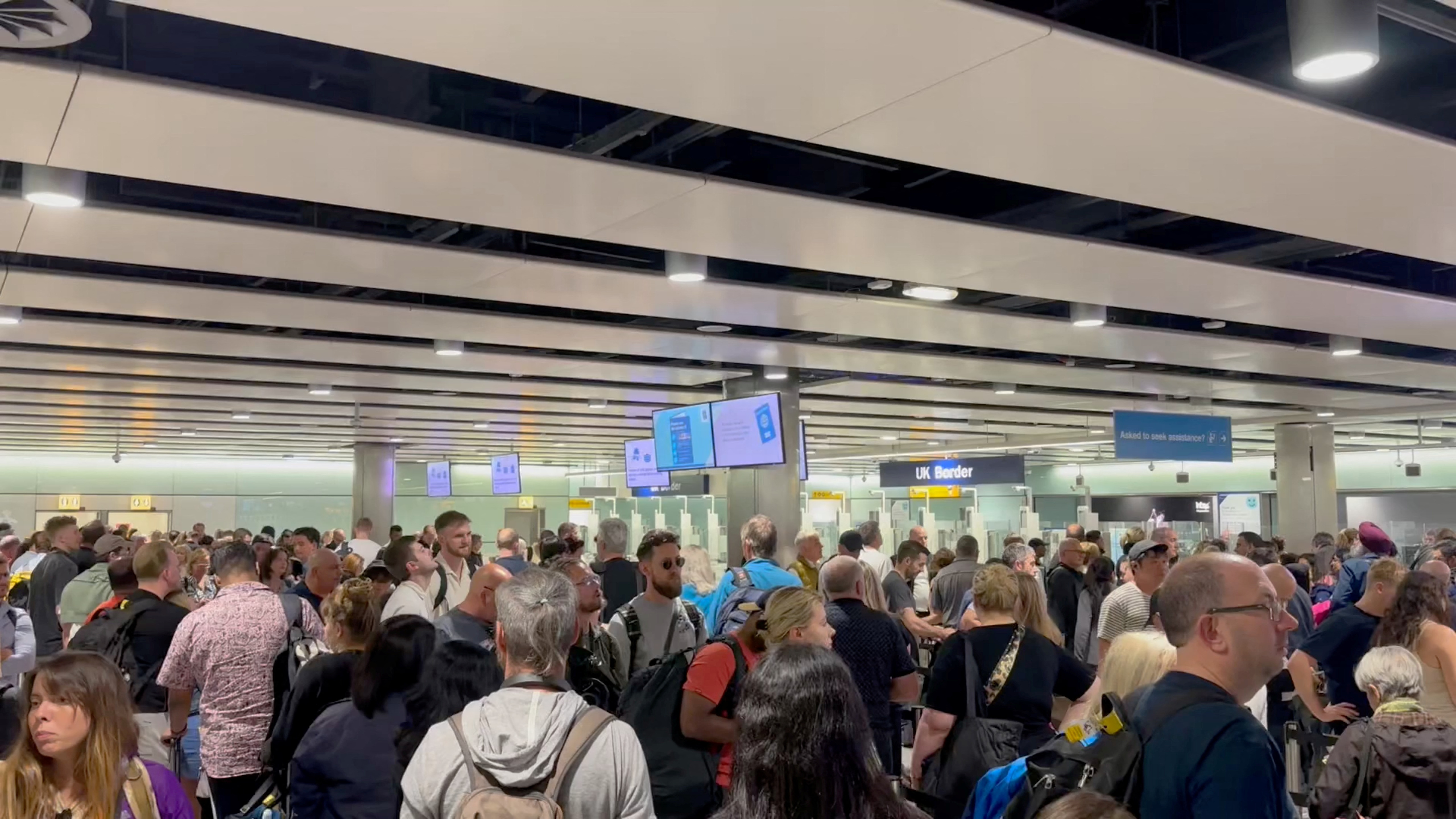 People wait in line at Heathrow airport, after the Border Force suffered a nationwide technical issue that affected passport control, in London