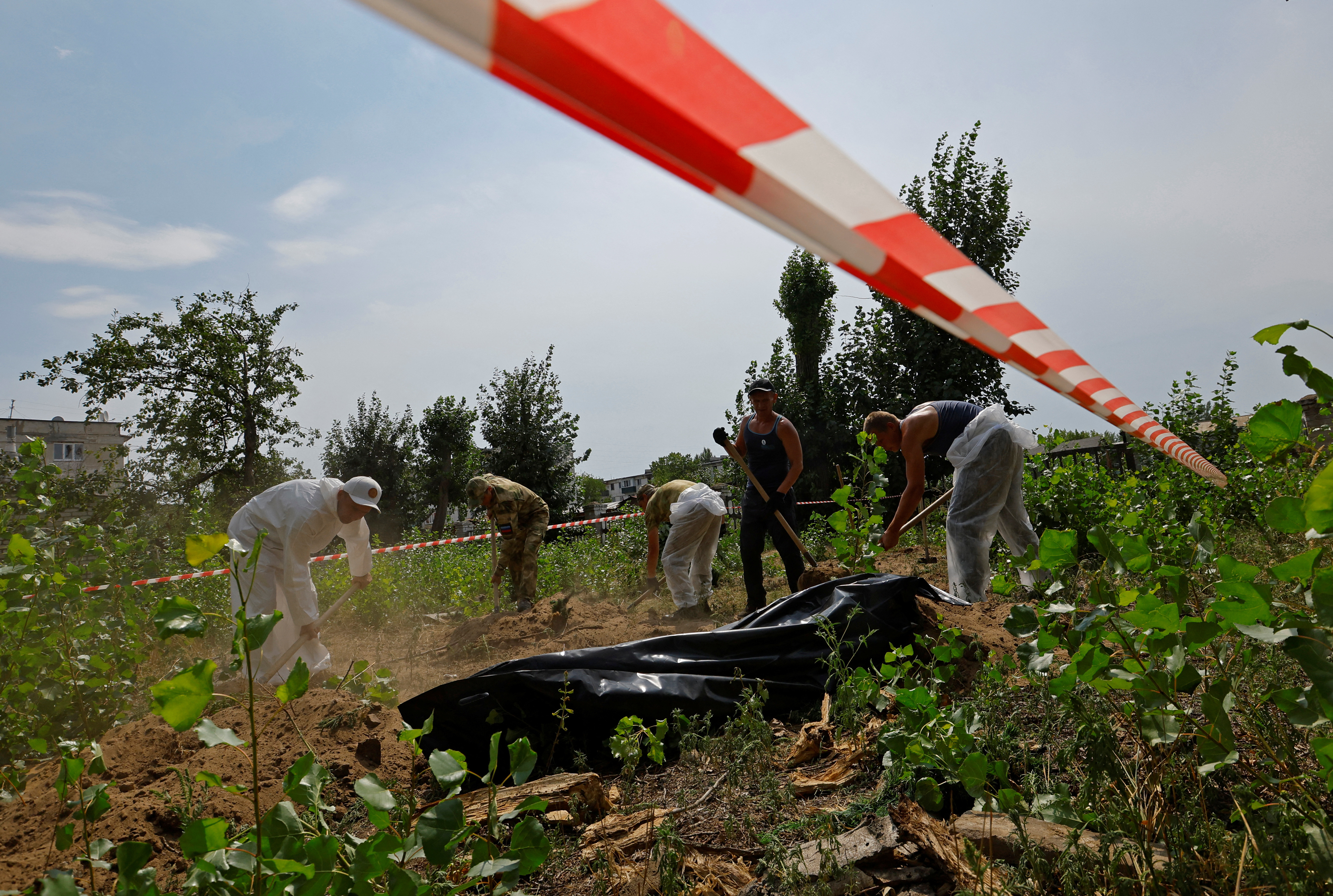 Specialists exhume bodies of civilians hastily buried during fighting in Rubizhne