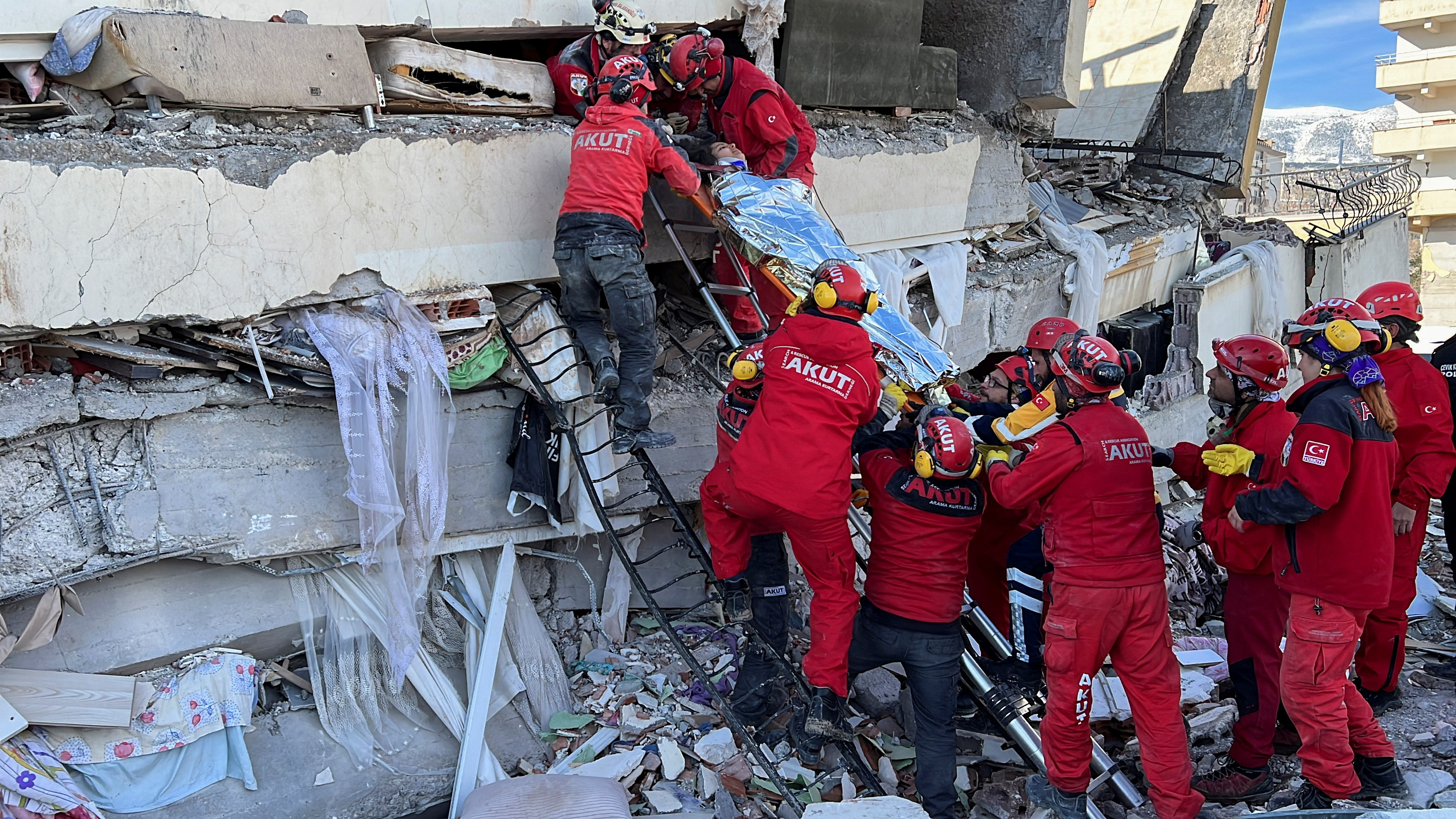 Rescuers carry a woman after she was evacuated from under a collapsed building following an earthquake in Kahramanmaras