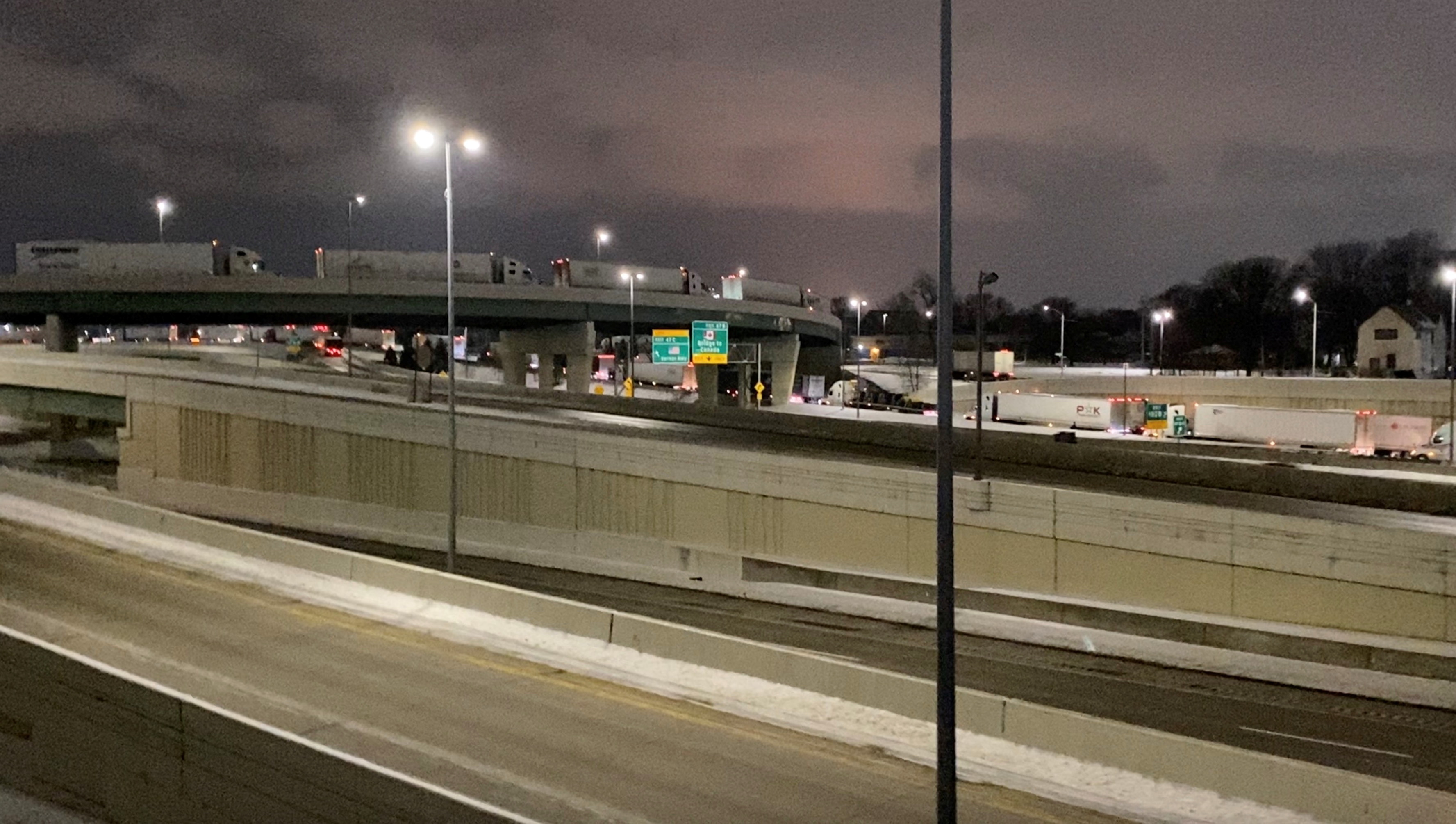 Truckers stand in line as they block the Ambassador Bridge (not pictured) on the I-75 and I-96 highways in Detroit, Michigan, U.S., February 7, 2022,  in this still image taken from a handout video obtained by Reuters on February 8, 2022. Macomb County Scanner/Handout via REUTERS    