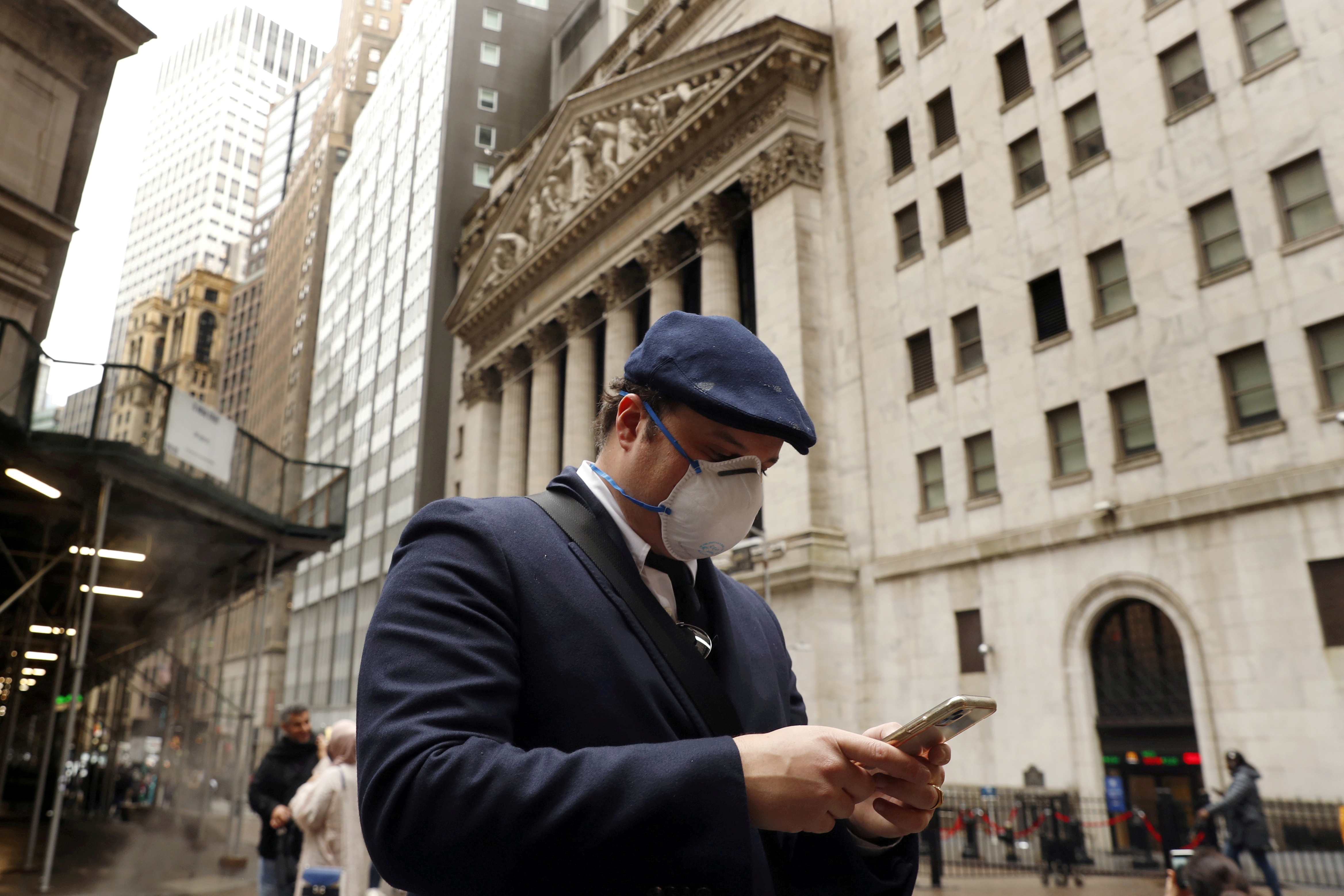 A man walks past the New York Stock Exchange on the corner of Wall and Broad streets in New York City, New York, U.S., March 13, 2020. REUTERS/Lucas Jackson/File Photo