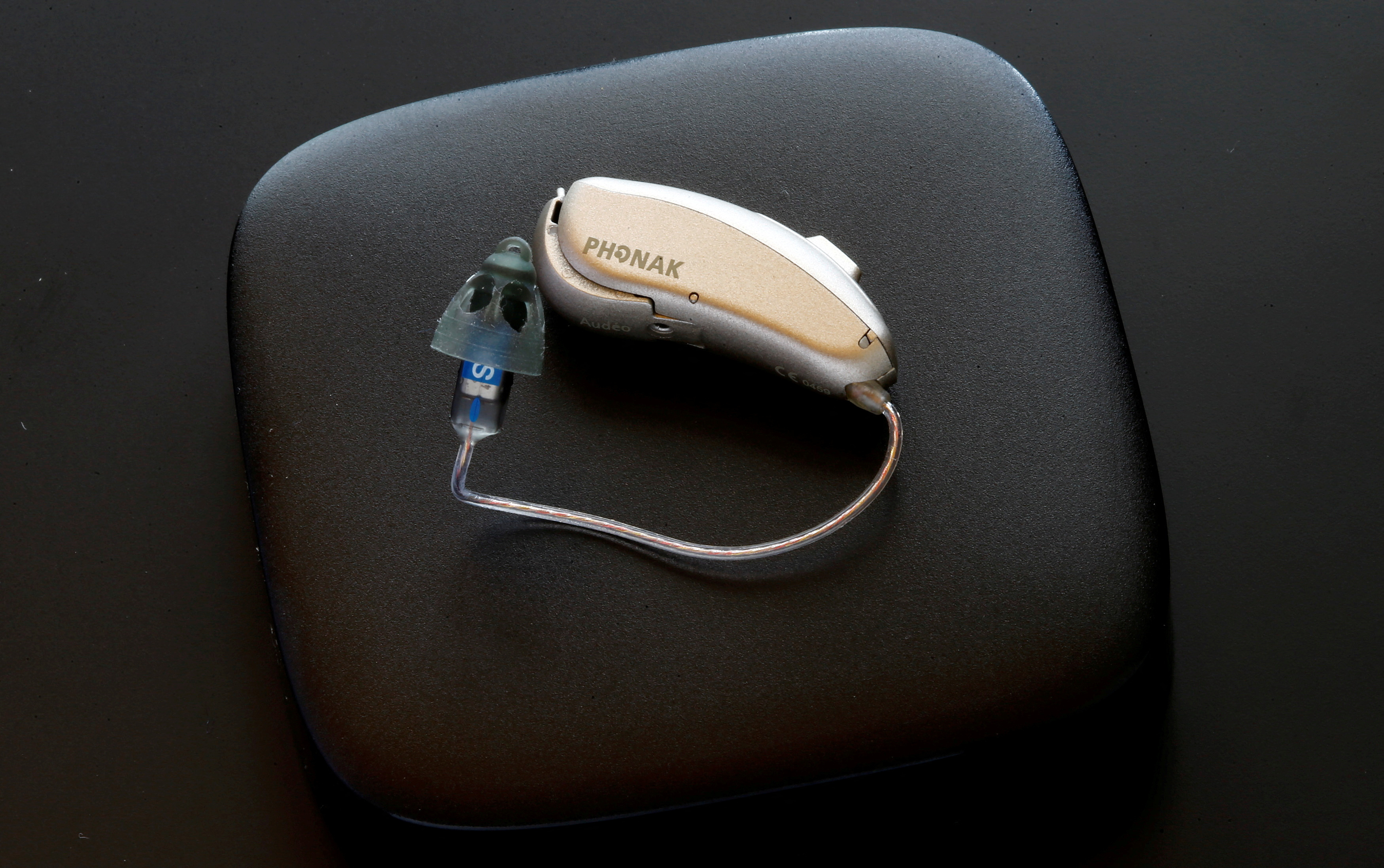 Phonak Audeo B-Direct hearing aid of Swiss manufacturer Sonova lies on a Phonak TV Connector in Staefa