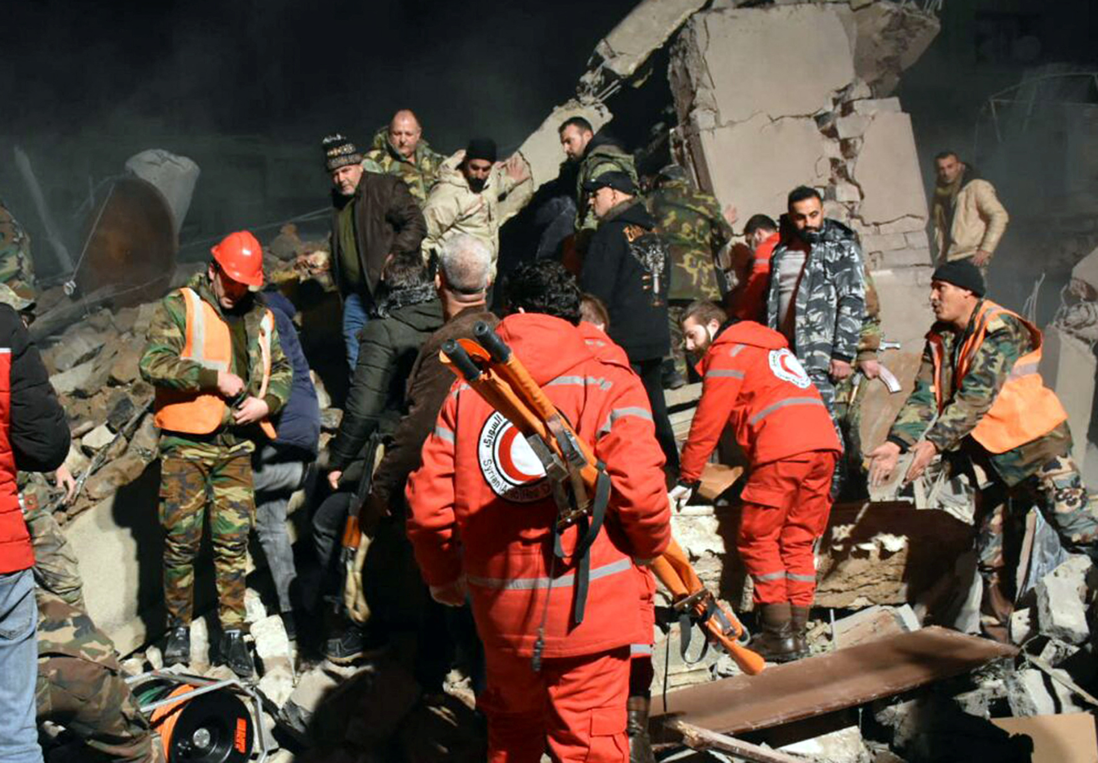 Rescuers search for survivors under the rubble of a damaged building in Homs province