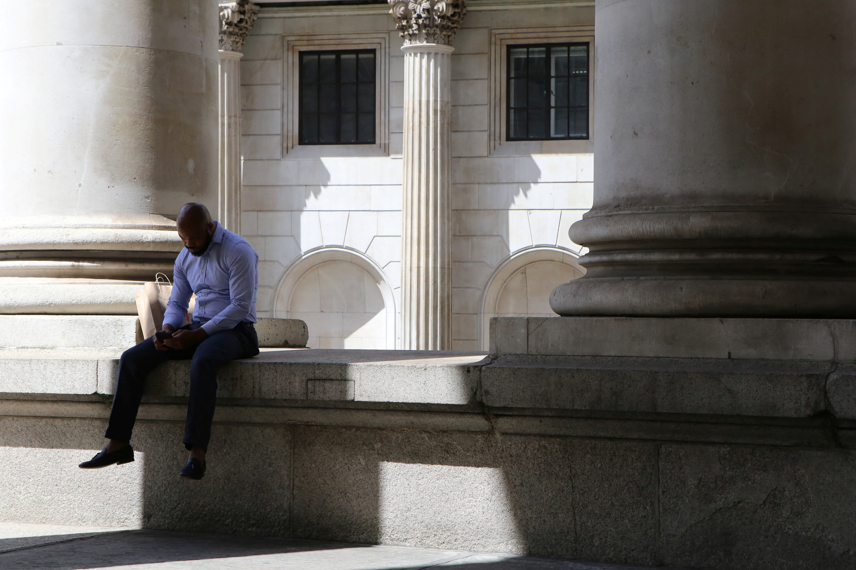 People relax in front of the Bank of England in London's financial district