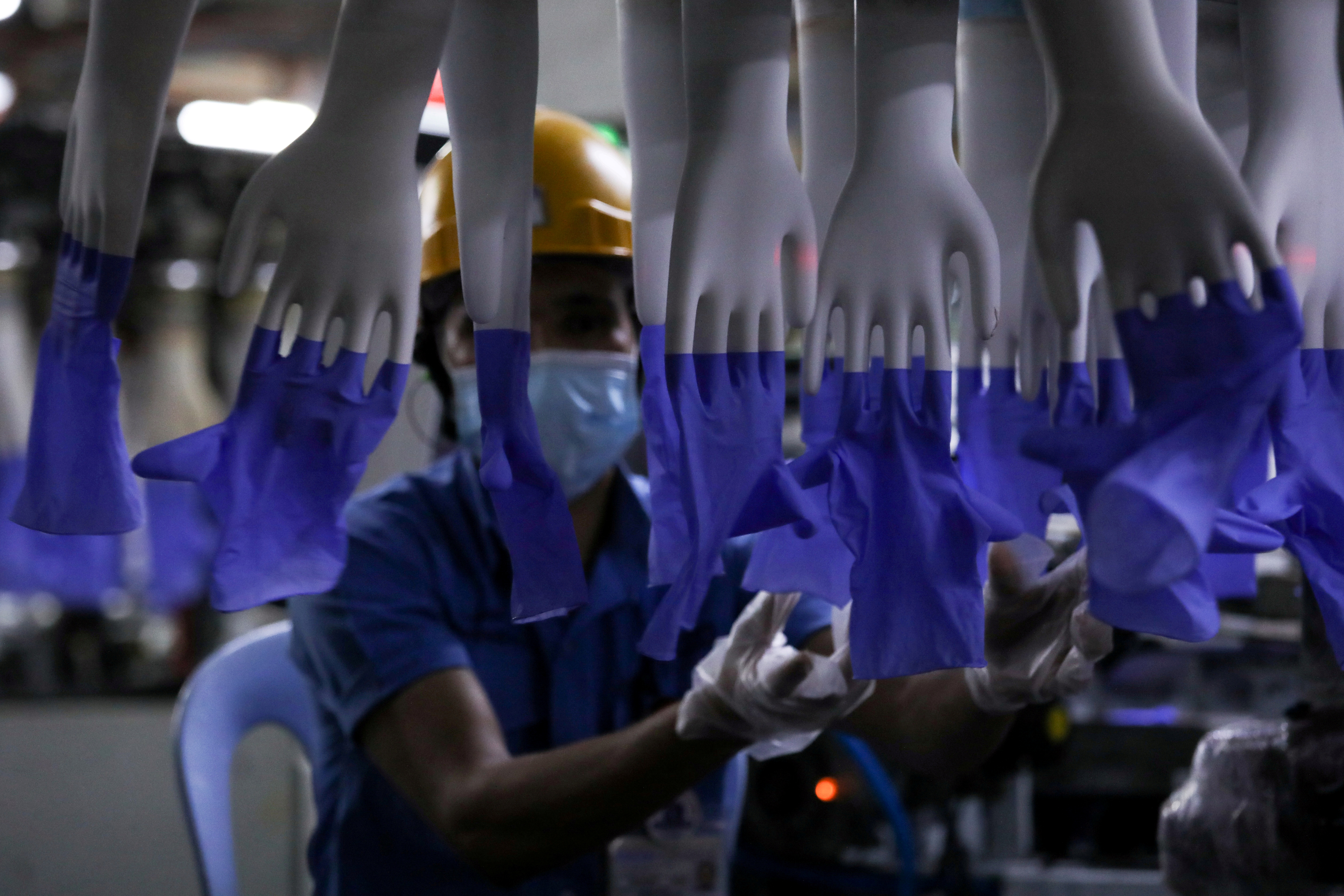 A worker inspects newly-made gloves at Top Glove factory in Shah Alam
