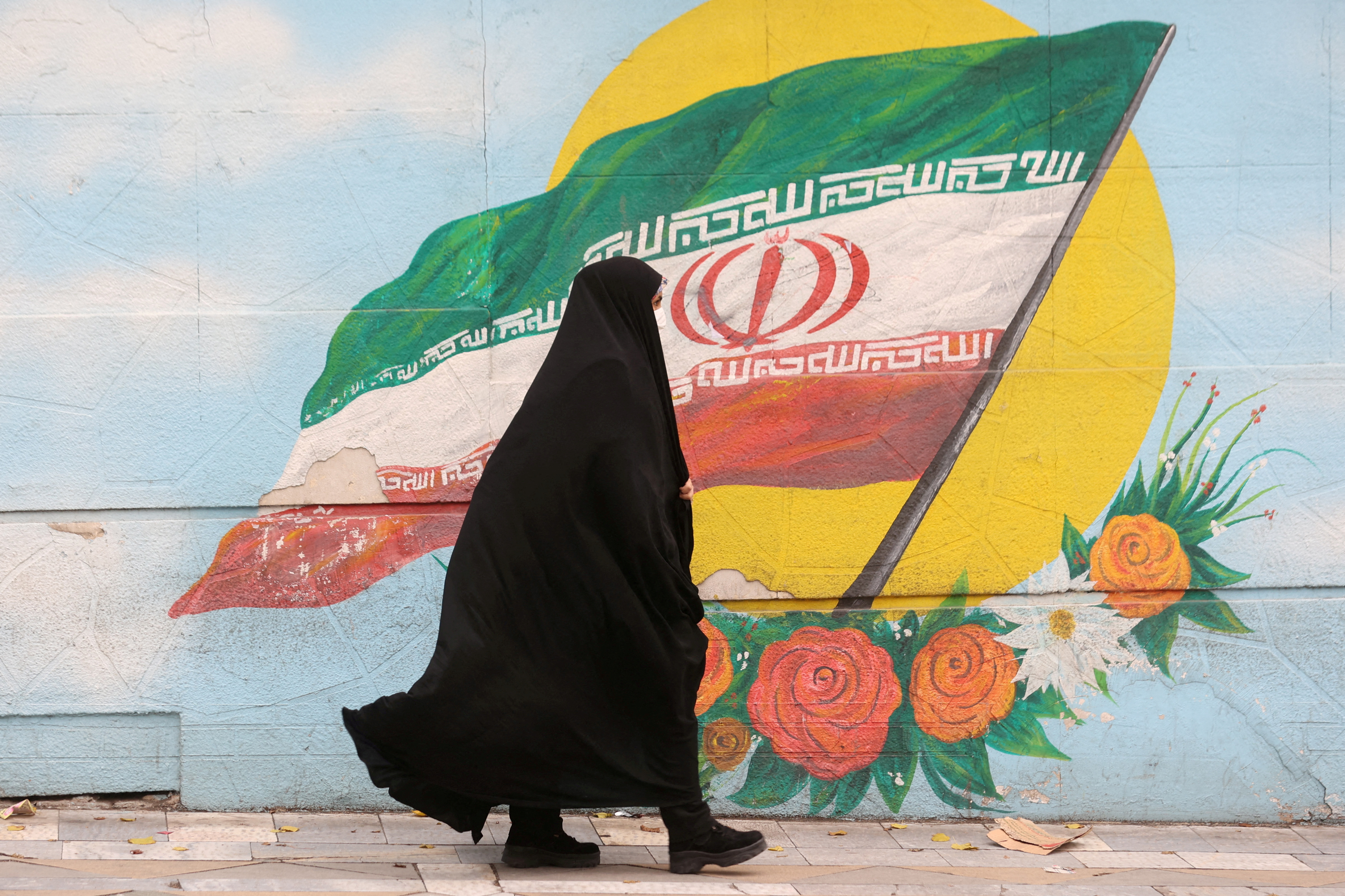 A woman walks down a street in Tehran, Iran
