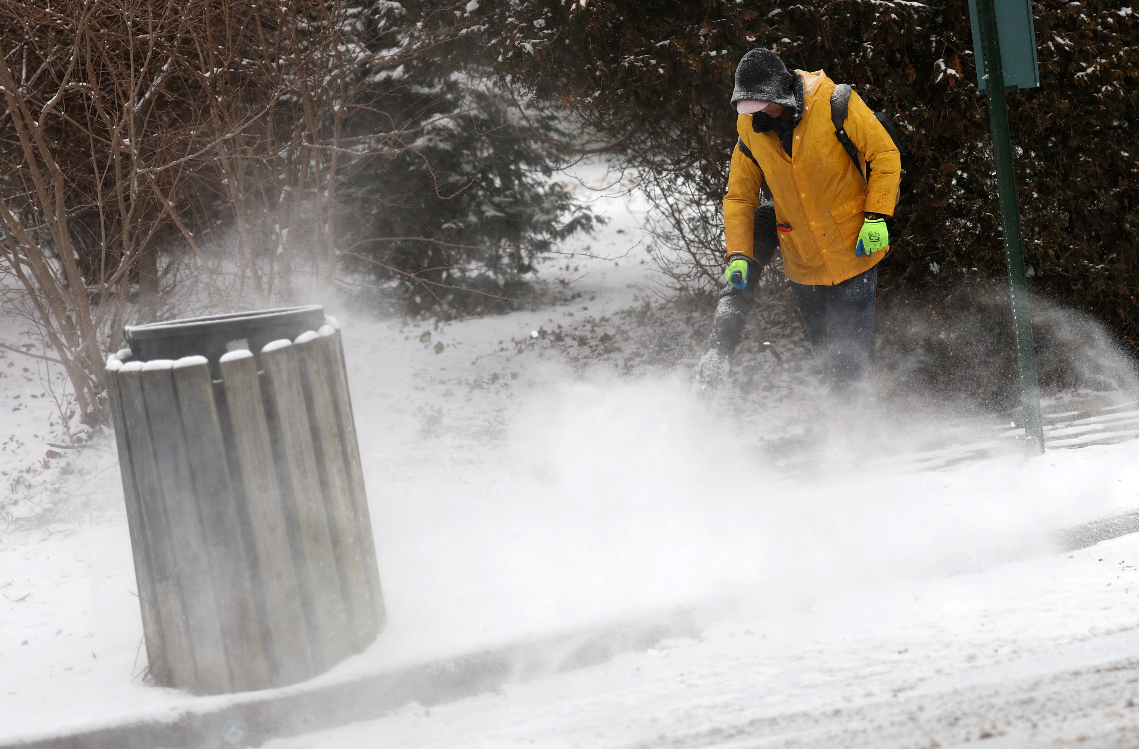 Man blows snow off sidewalk during winter weather in New York City suburb of Nyack