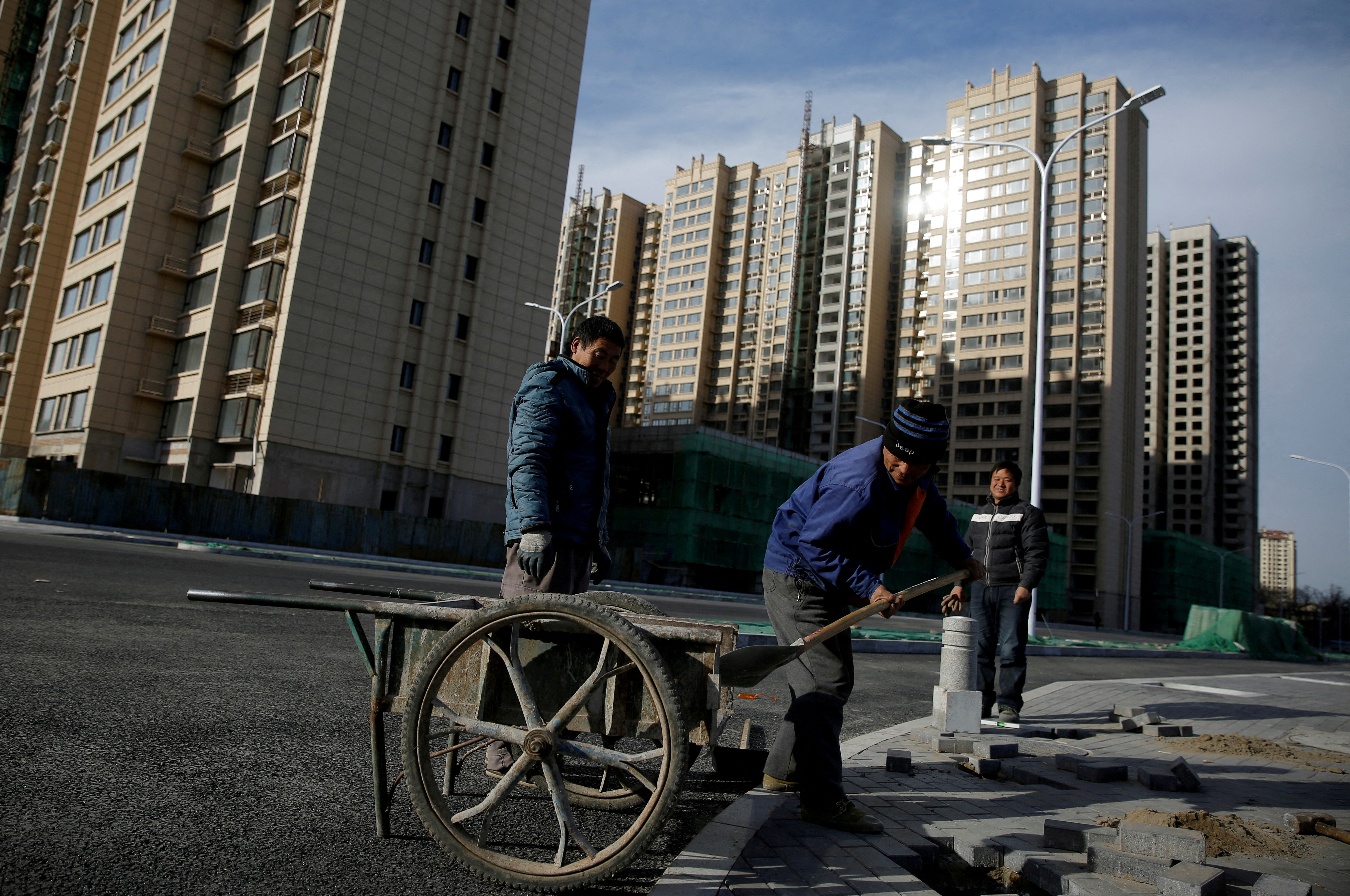 Men work near residential apartment blocks under construction on the outskirts of Beijing, China