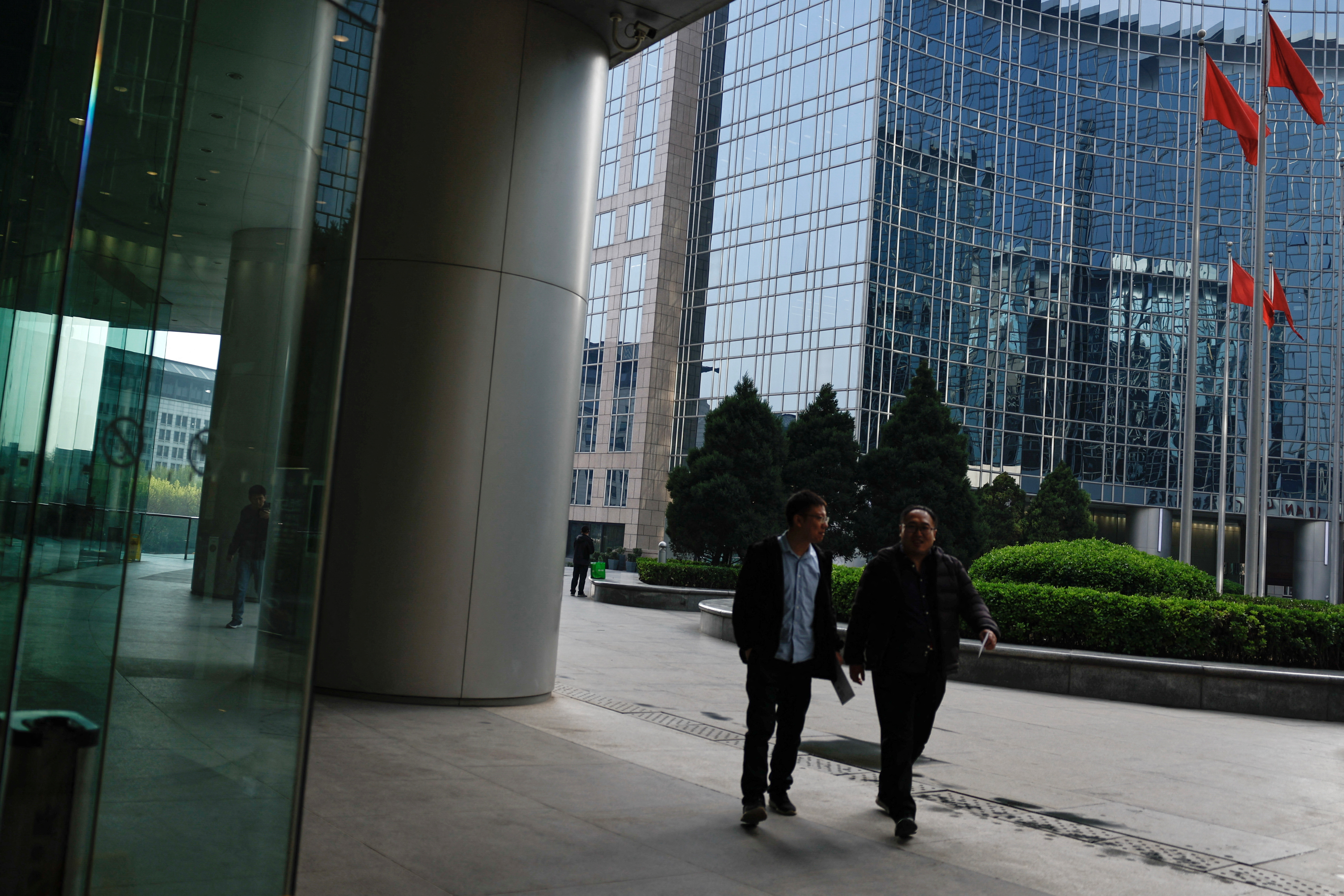 People walk past an office and shopping complex in Beijing