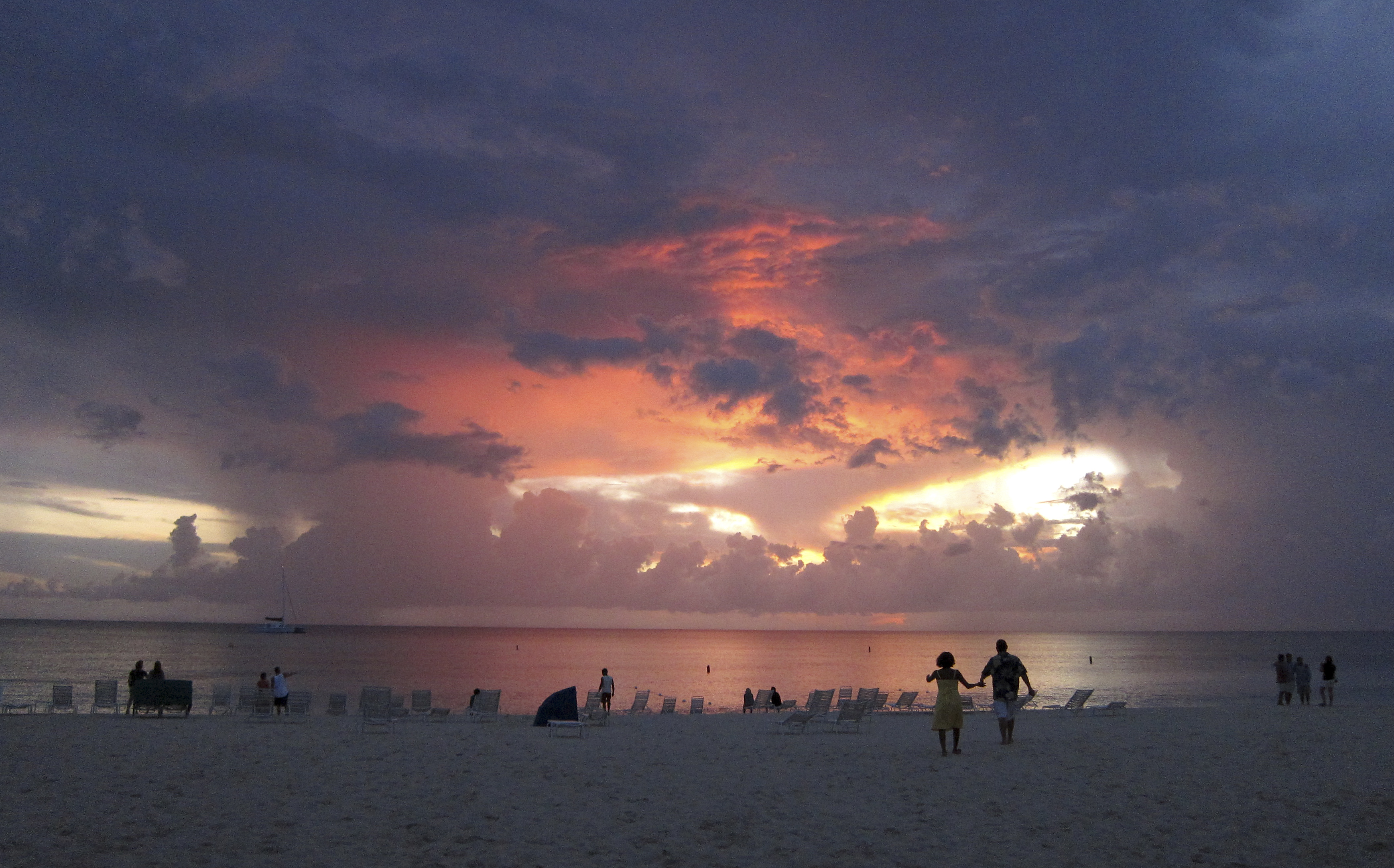 Tourists walk on Seven Mile Beach at sunset in George Town, Cayman Islands July 28, 2011.