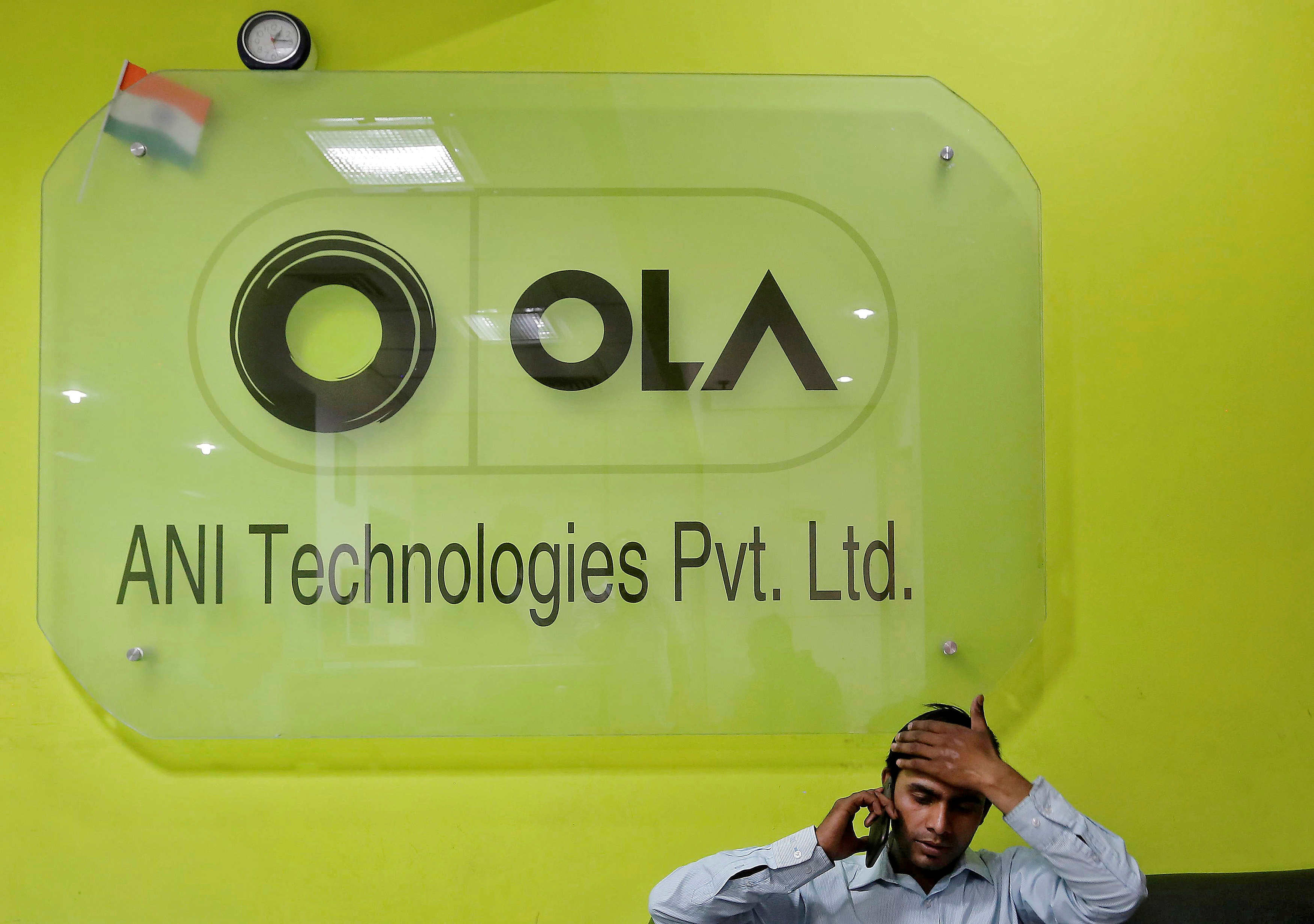 An employee speaks over his phone as he sits at the front desk inside the office of Ola cab service in Gurugram, previously known as Gurgaon, on the outskirts of New Delhi, India, April 20, 2016.  REUTERS/Anindito Mukherjee/File Photo