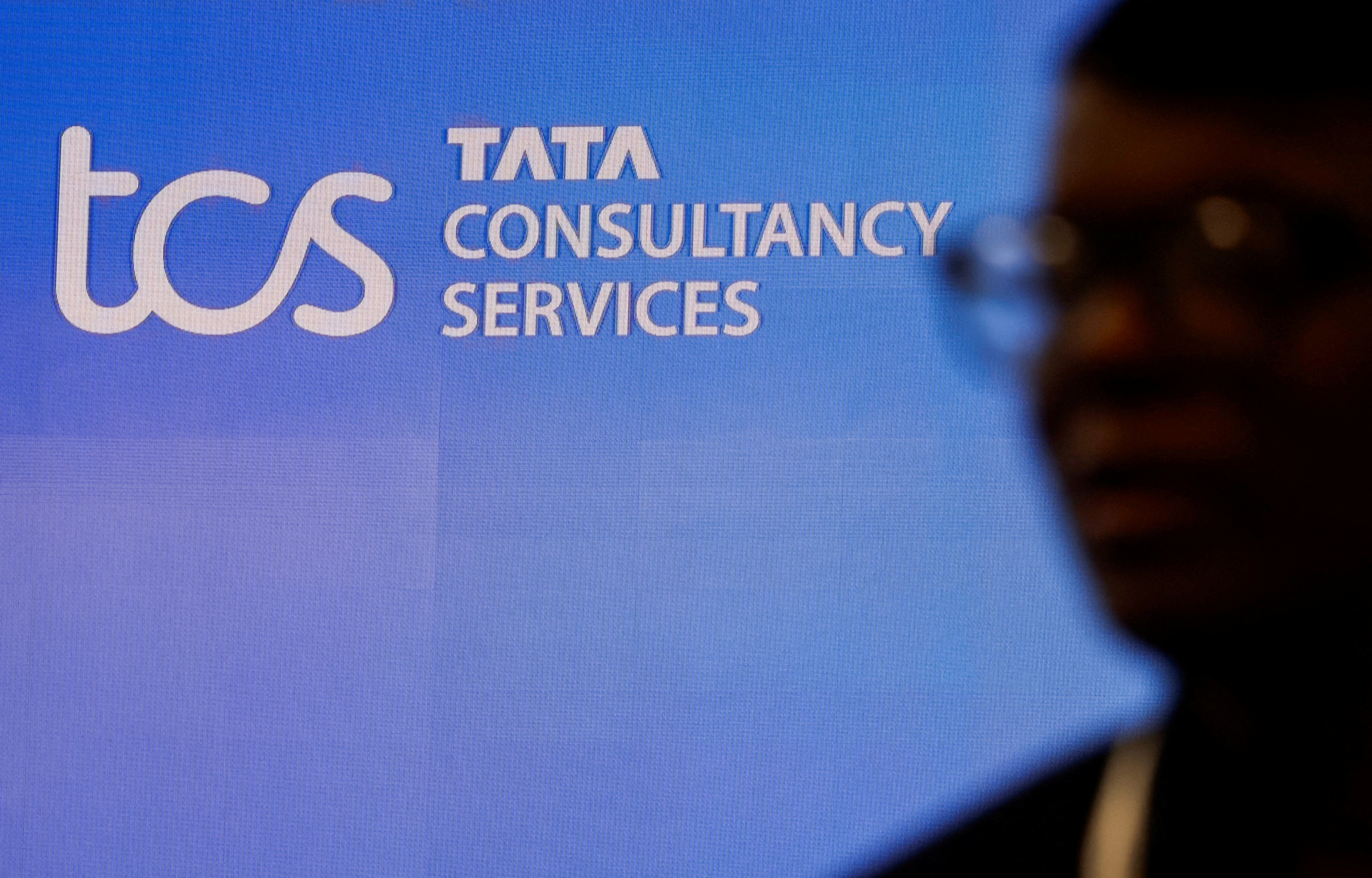 A man walks past a logo of Tata Consultancy Services (TCS) before a press conference announcing the company's quarterly results in Mumbai
