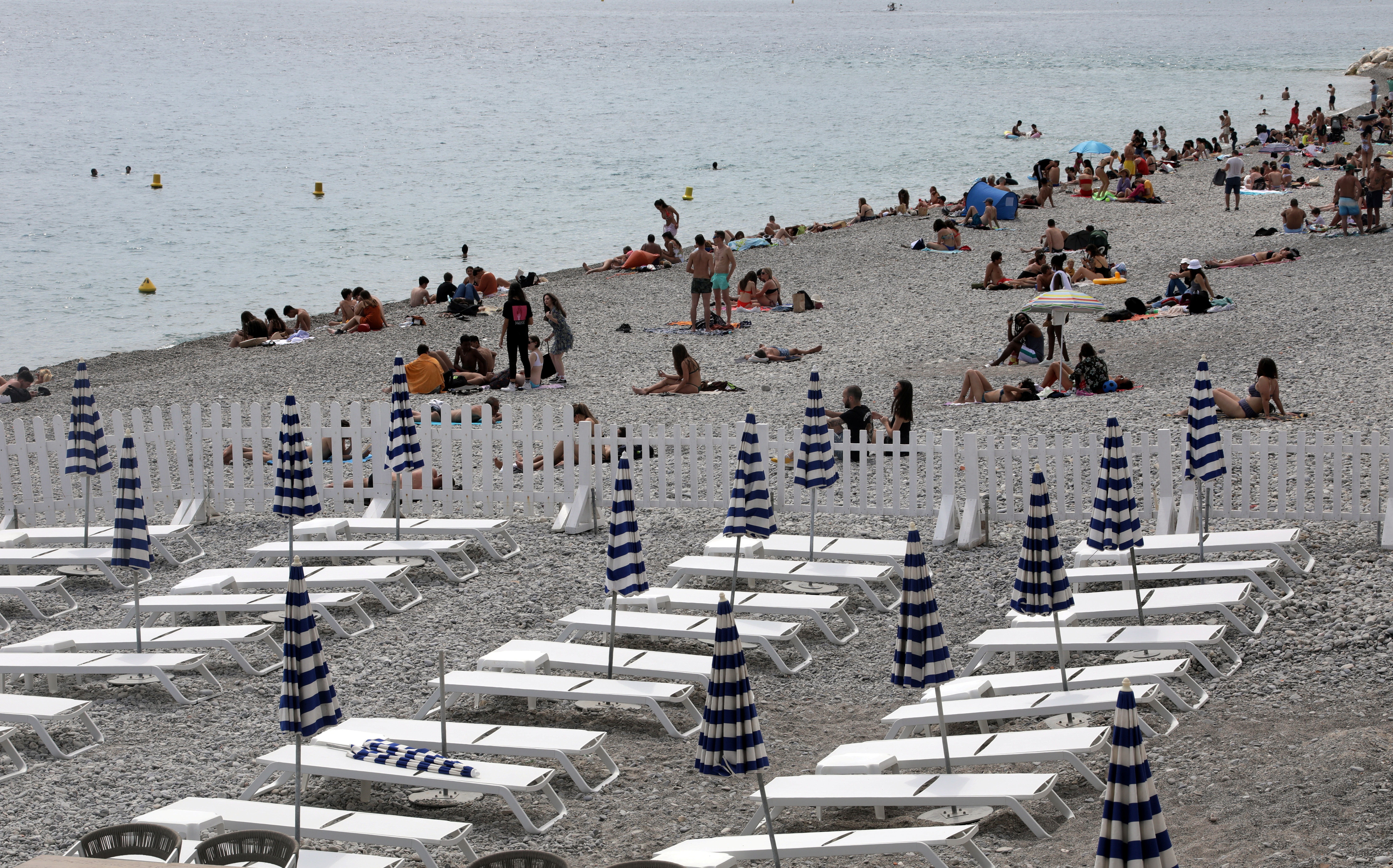 Deckchairs are aligned respecting social distancing on a private beach in Nice
