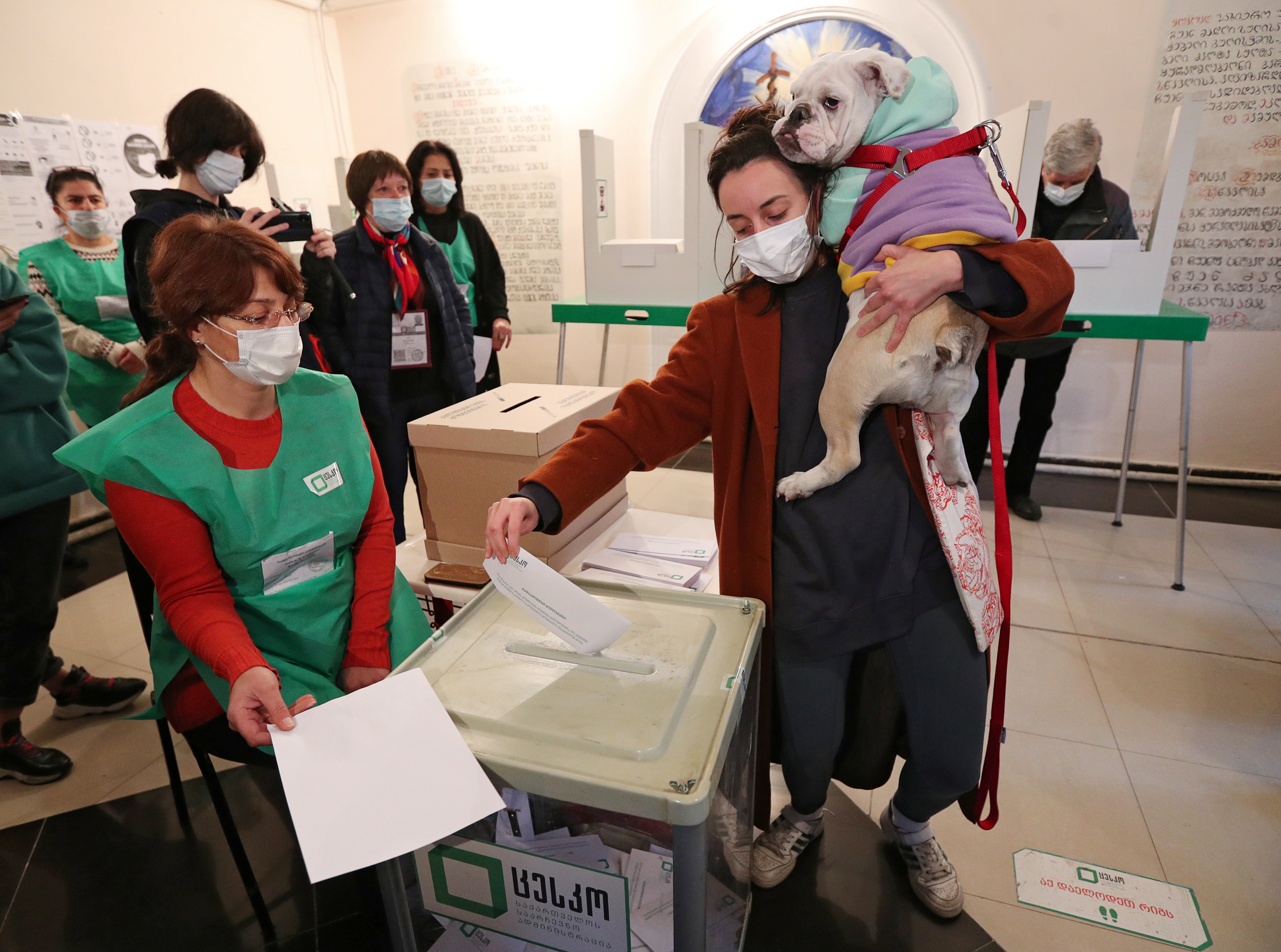 A woman holds her dog as she casts a ballot during the municipal elections in Tbilisi