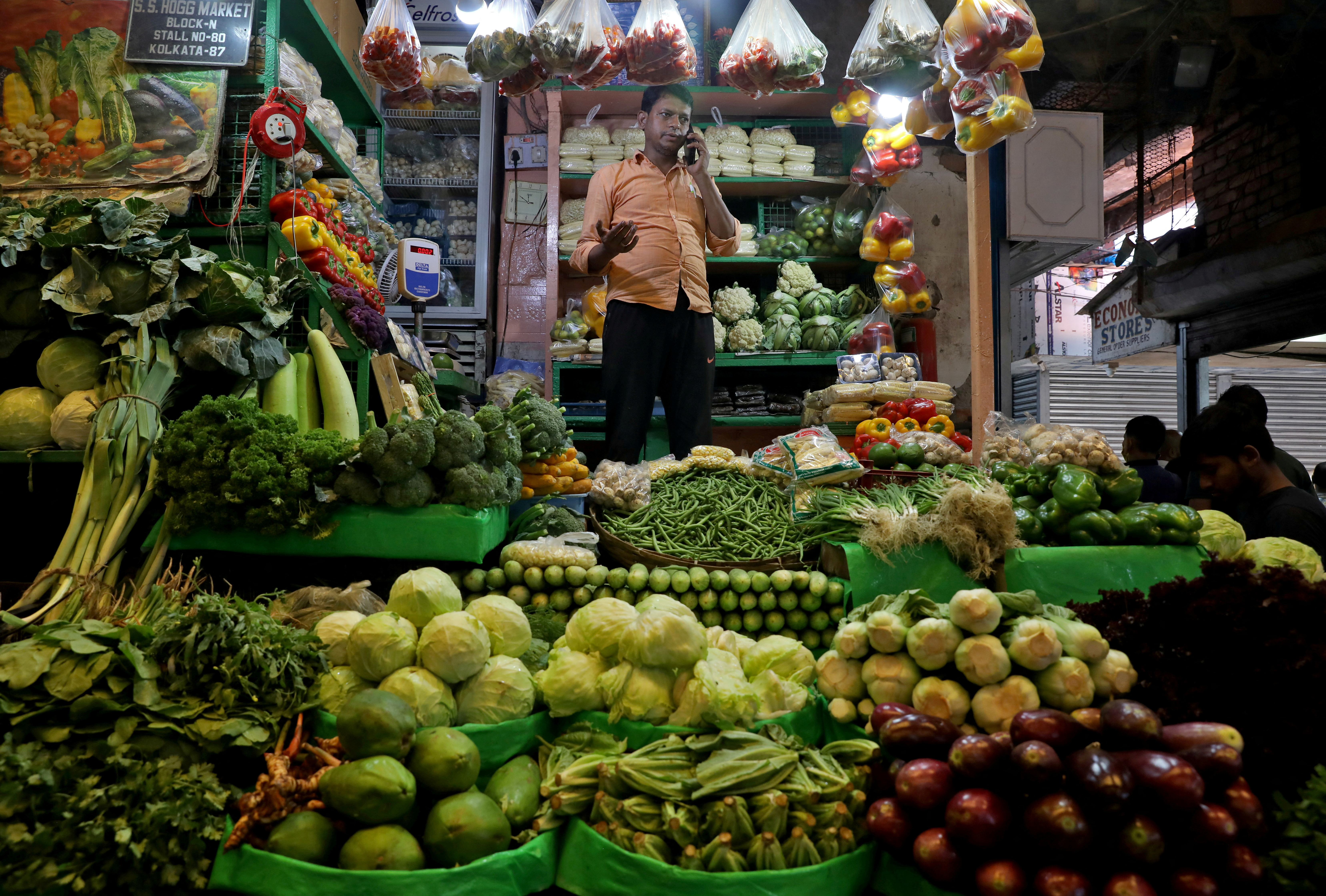 Debashis Dhara, a vegetable vendor, speaks on his mobile phone at a retail market area in Kolkata