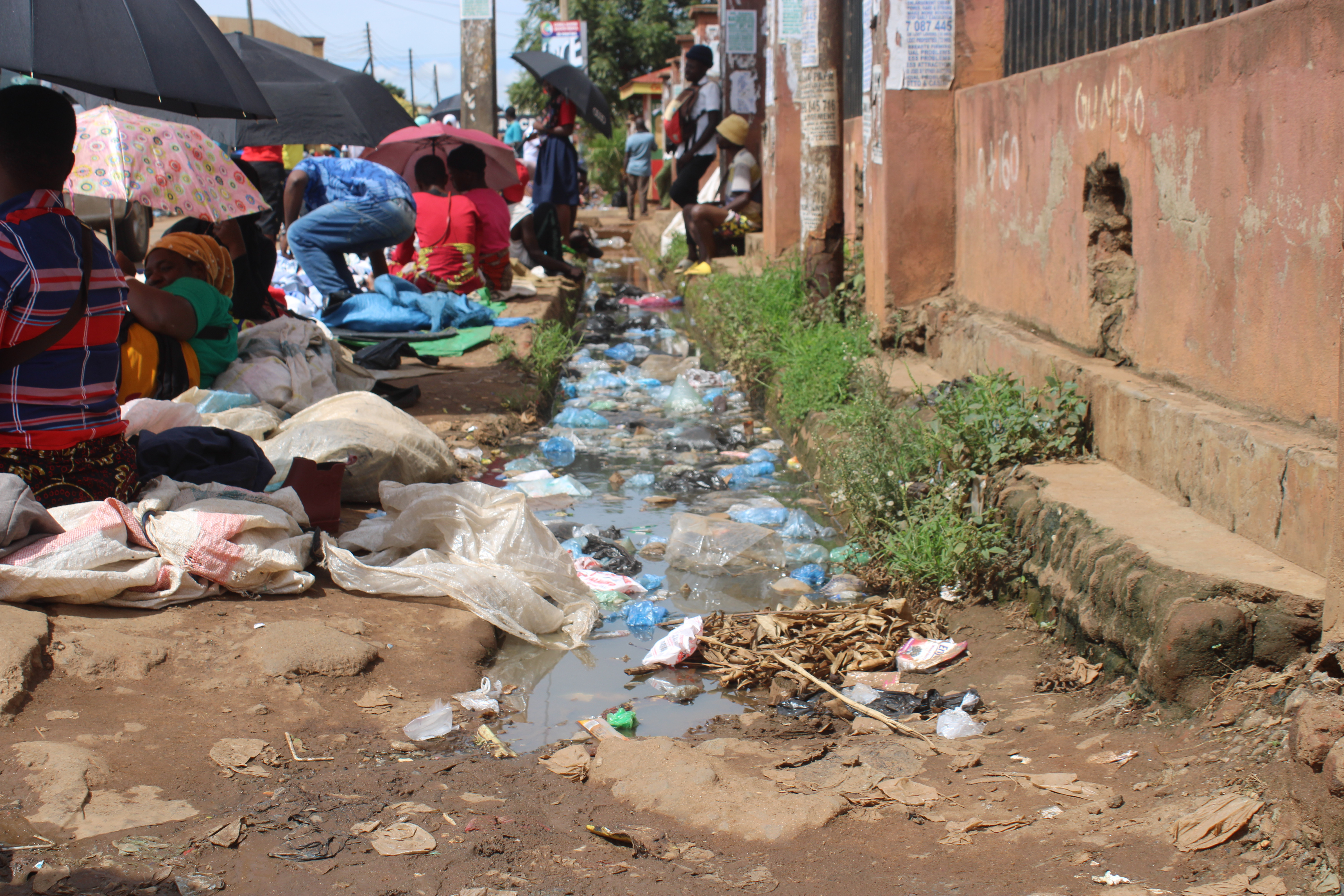 Vendors selling clothes and other merchandise in the city of Lilongwe, Malawi. Behind them is polluted water. Poor drainage facilities is one of the problems in the cities. January 11, 2023. Kondwani Magombo/Thomson Reuters Foundation