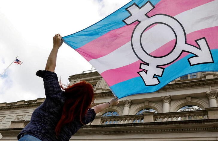 A person holds up a flag during rally to protest the Trump administration's reported transgender proposal to narrow the definition of gender to male or female at birth in New York