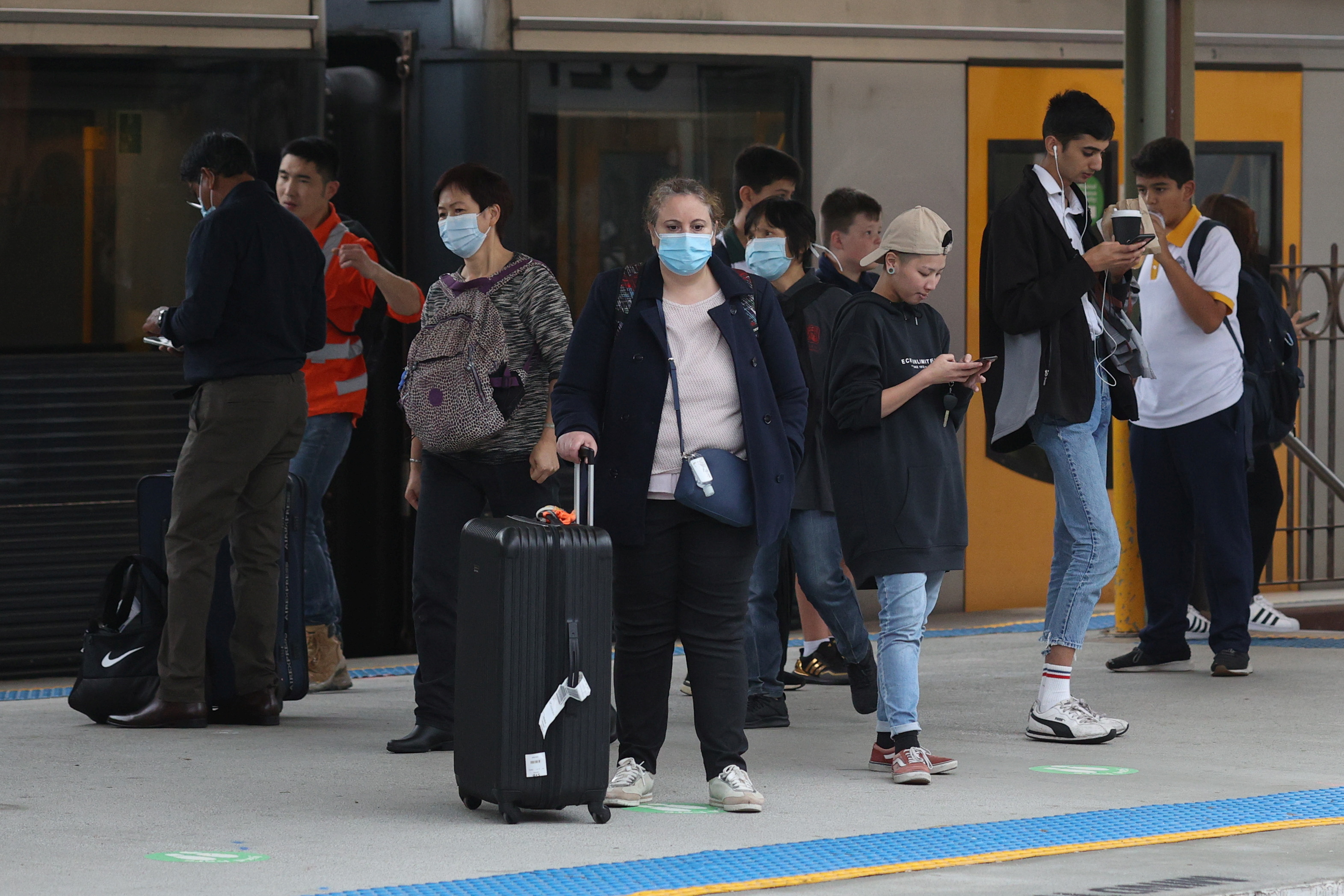 People wear protective masks after new cases of COVID-19 were reported in Sydney