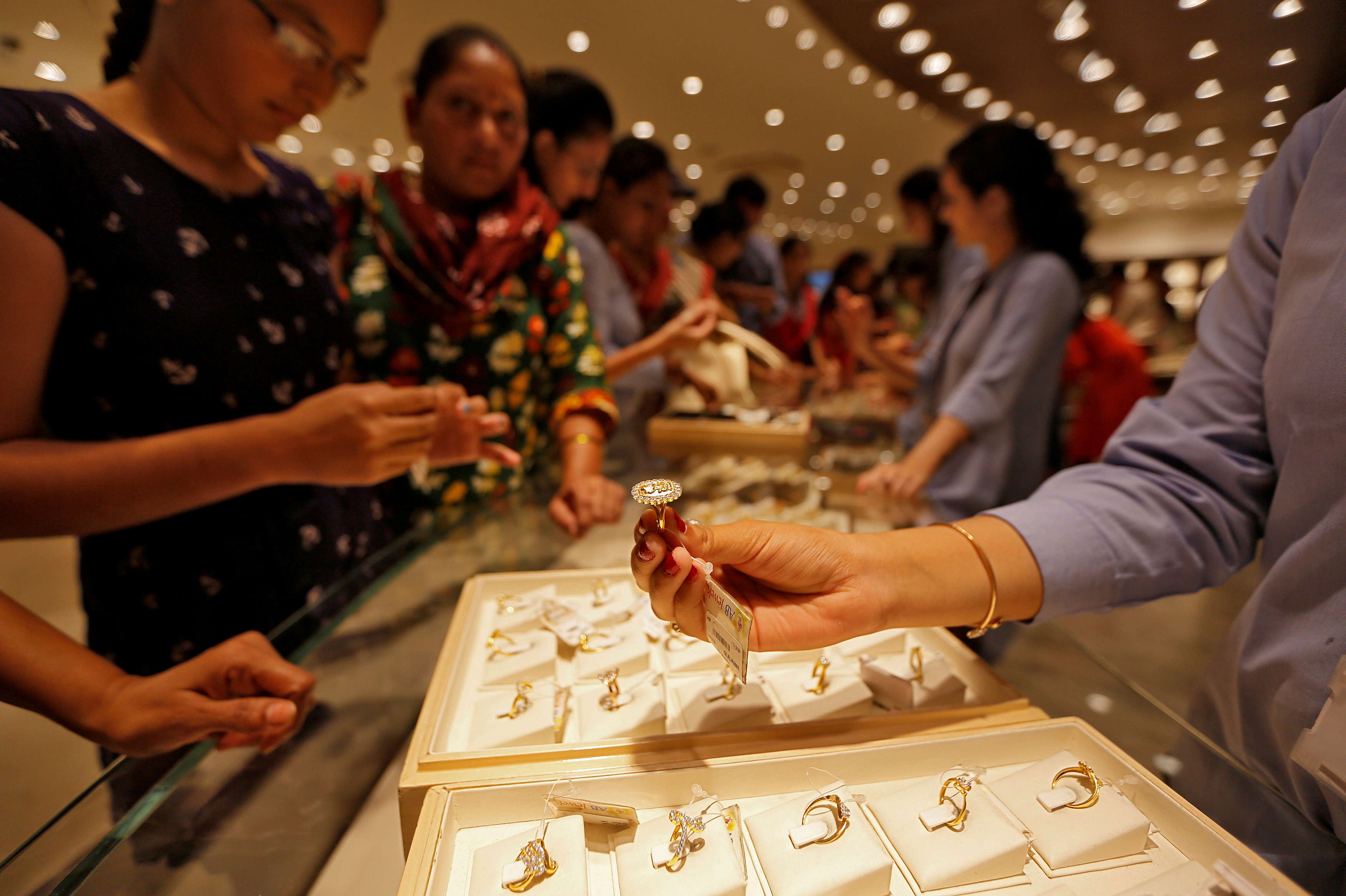 A sales person shows a gold ring to customers at a jewellery showroom during Dhanteras, a Hindu festival associated with Lakshmi, the goddess of wealth, in Ahmedabad