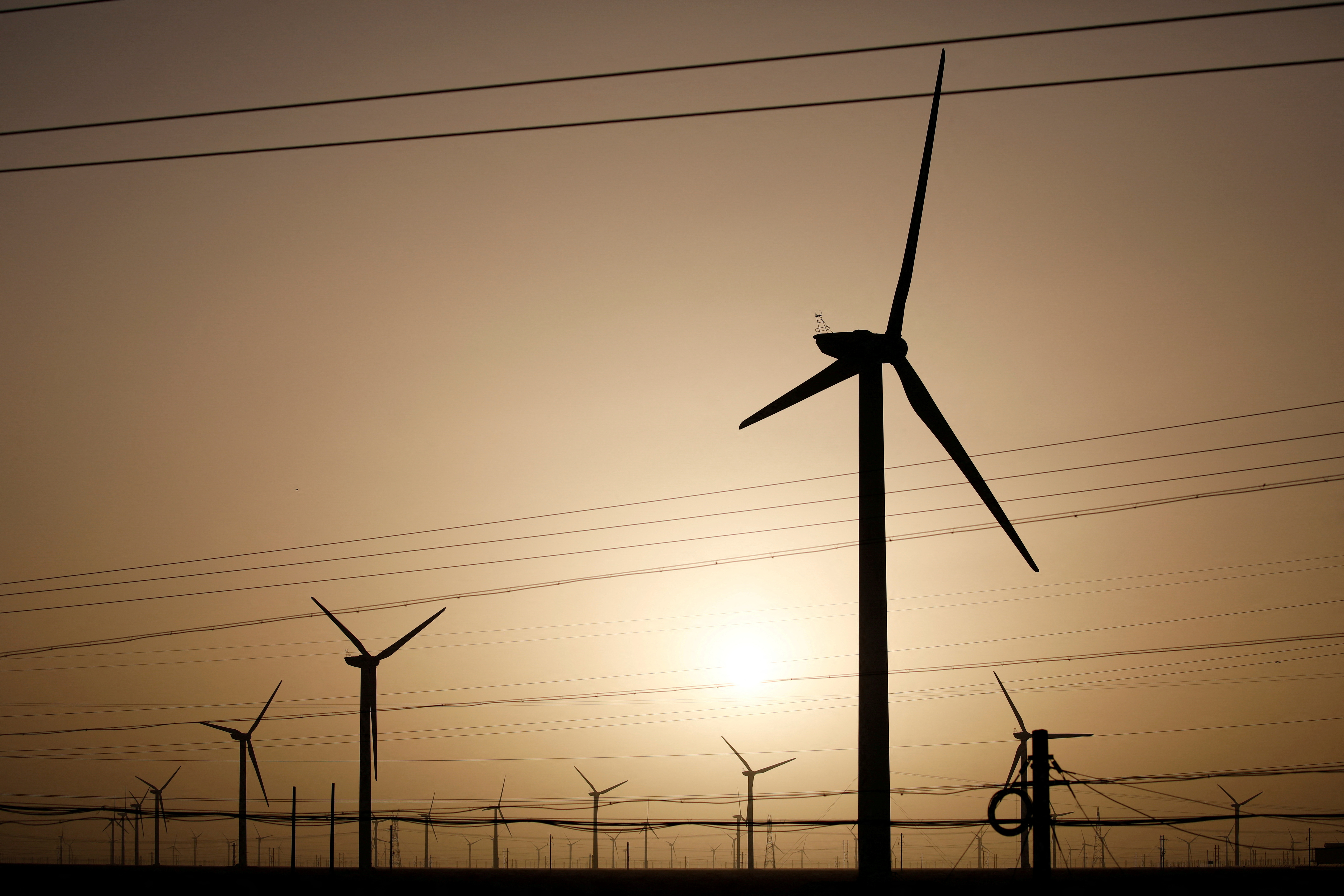 Wind turbines stand on a power station near Yumen