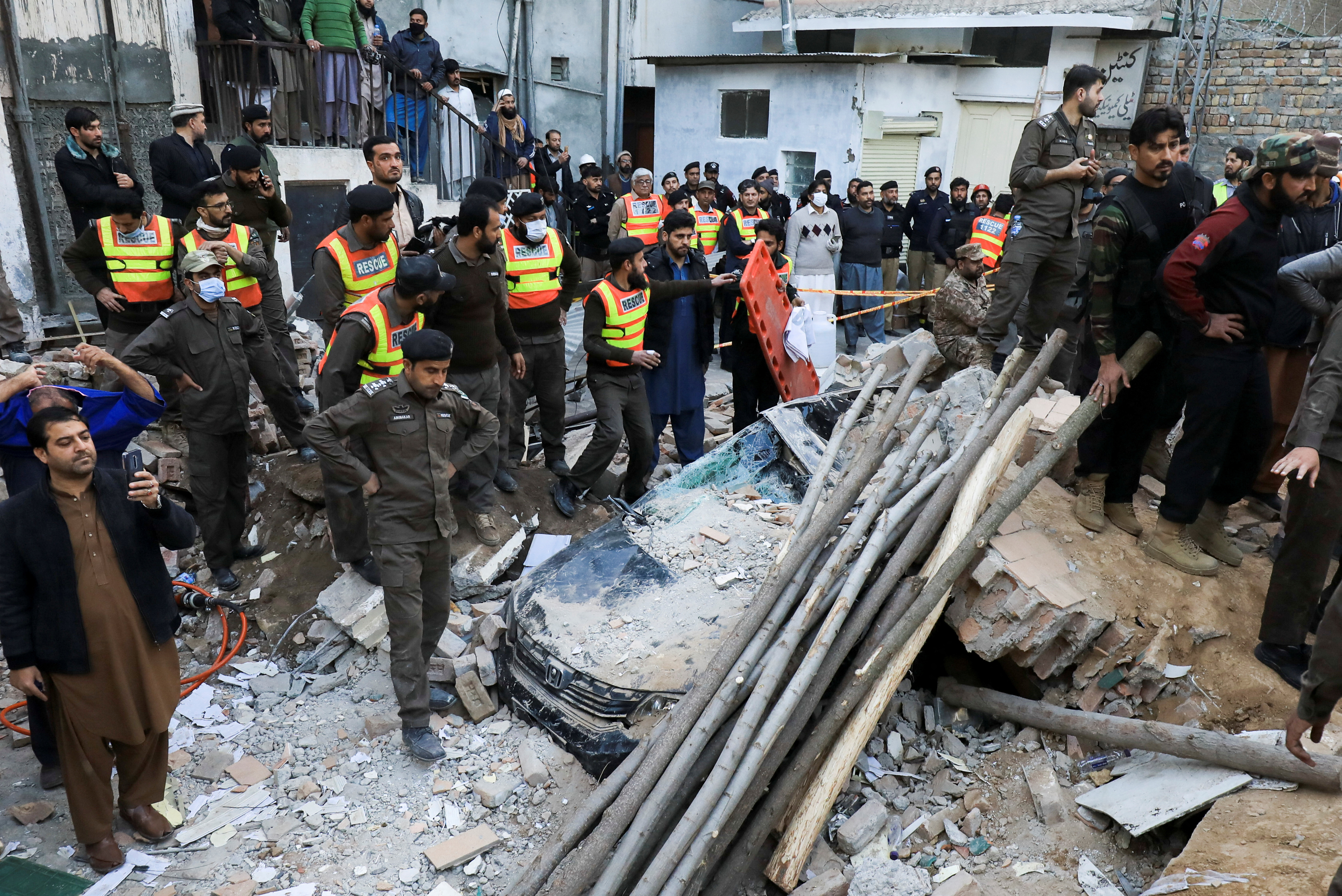 People and rescue workers gather amid the damages, after a suicide blast in a mosque in Peshawar