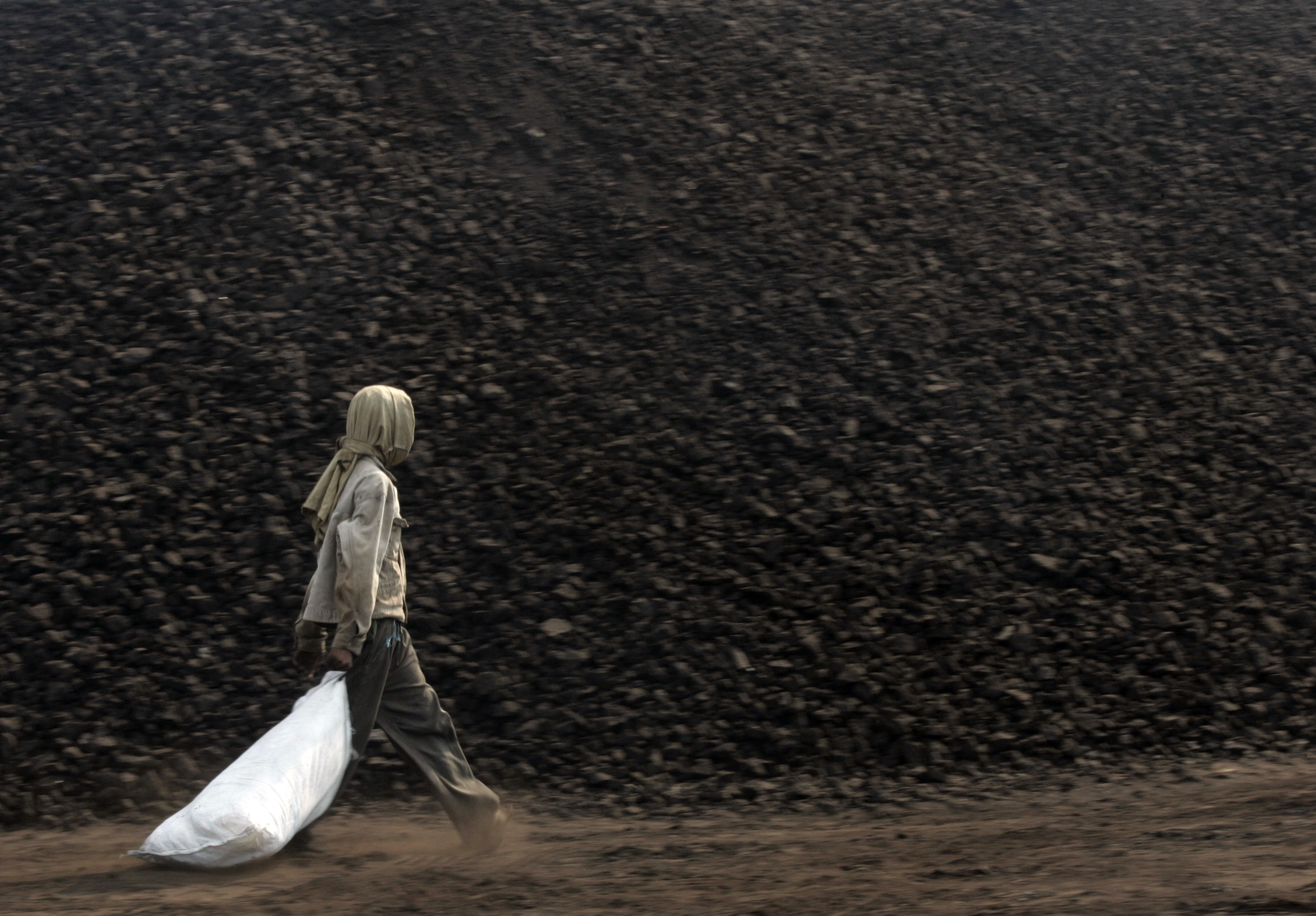 Worker carries a plastic bag as he walks in a coal stock pile port near Cilegon habour of West Java province