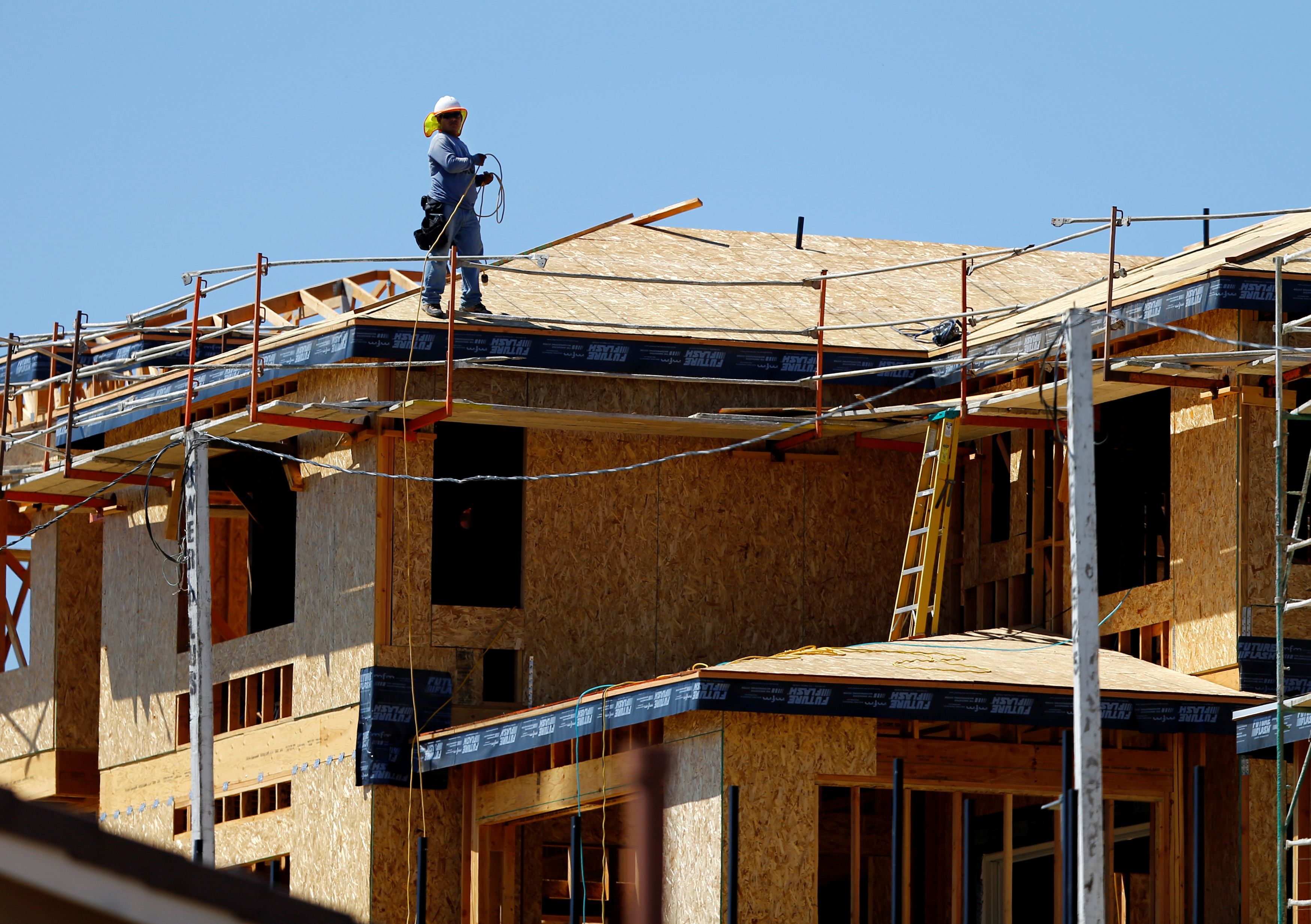 A worker walks on the roof of a new home under construction in Carlsbad
