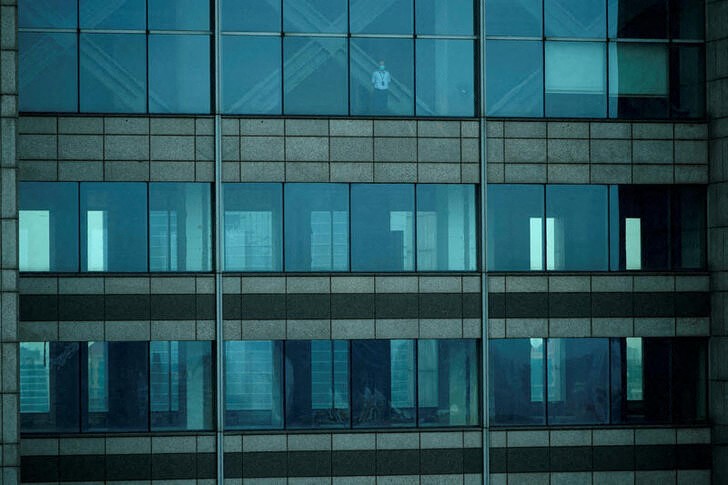 A man wearing a protective face mask is seen an empty office building in Lujiazui financial district in Pudong, in Shanghai