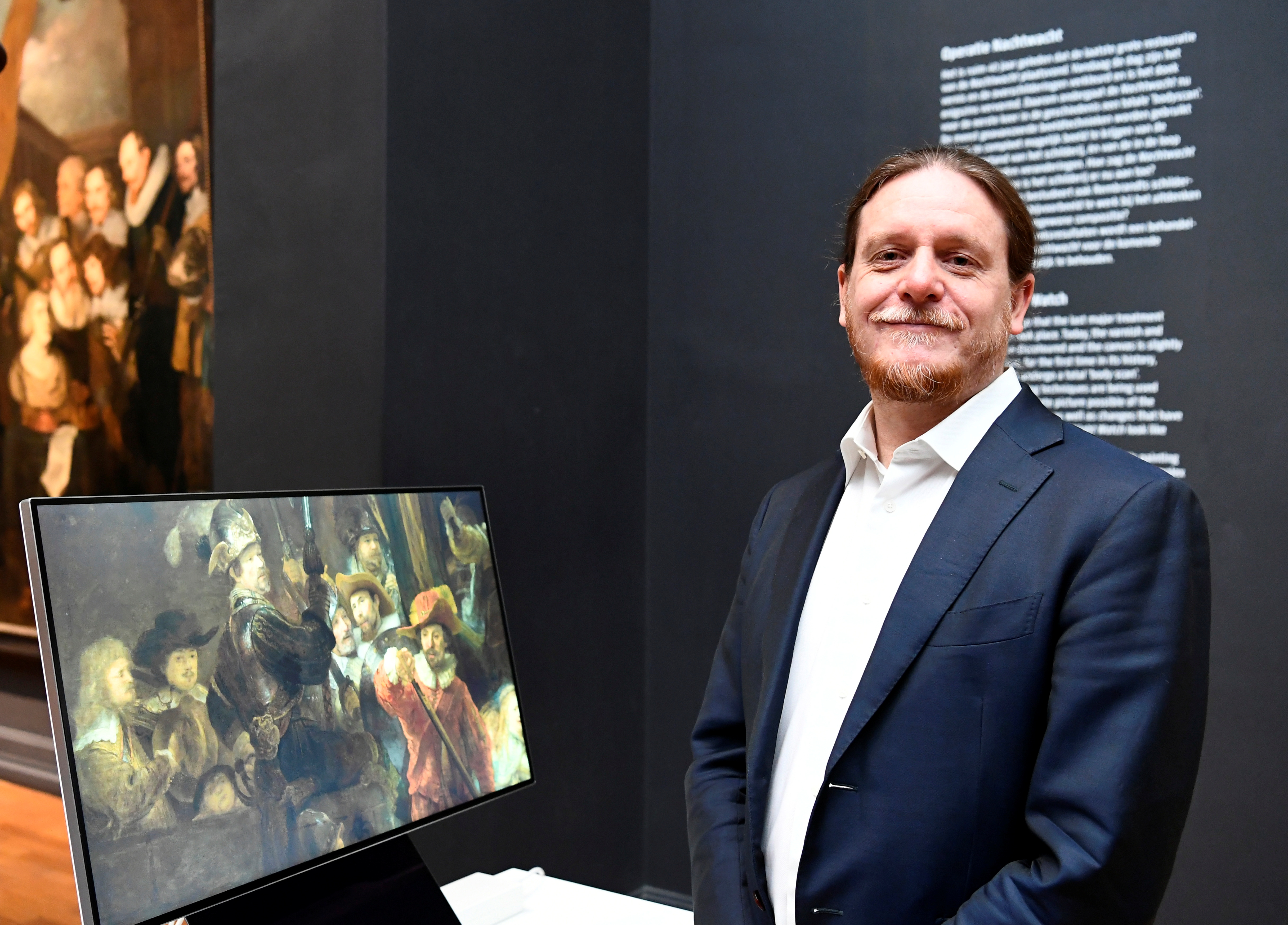 Robert Erdmann, senior scientist at the Rijksmuseum, shows Rembrandt's famed Night Watch on a screen, while the painting is back on display in what researchers say in its original size, with missing parts temporarily restored in an exhibition aided by artificial intelligence at Rijksmuseum in Amsterdam, Netherlands June 23, 2021. REUTERS/Piroschka van de Wouw