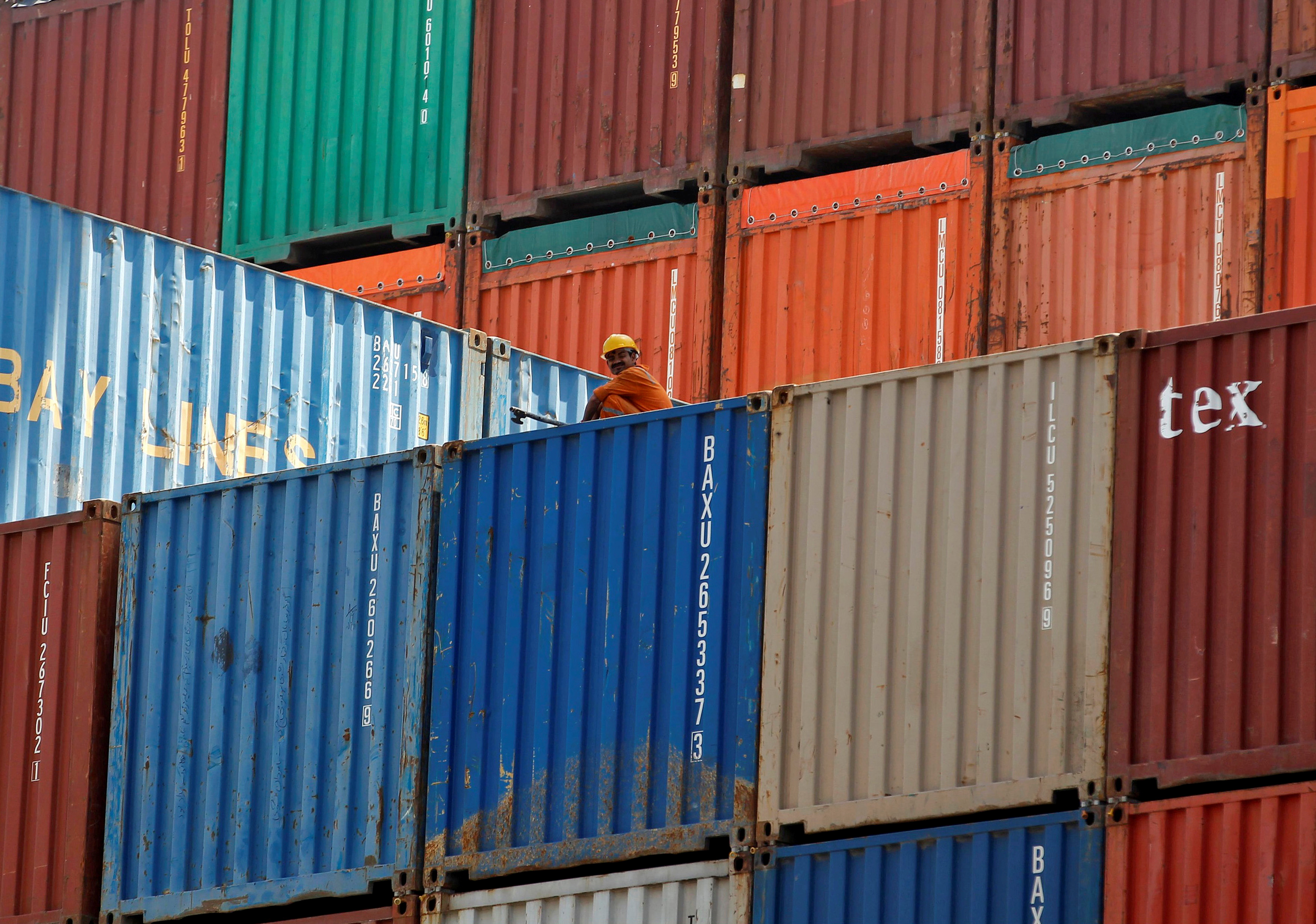 A worker sits on a ship carrying containers at Mundra Port in the western Indian state of Gujarat April 1, 2014. REUTERS/Amit Dave