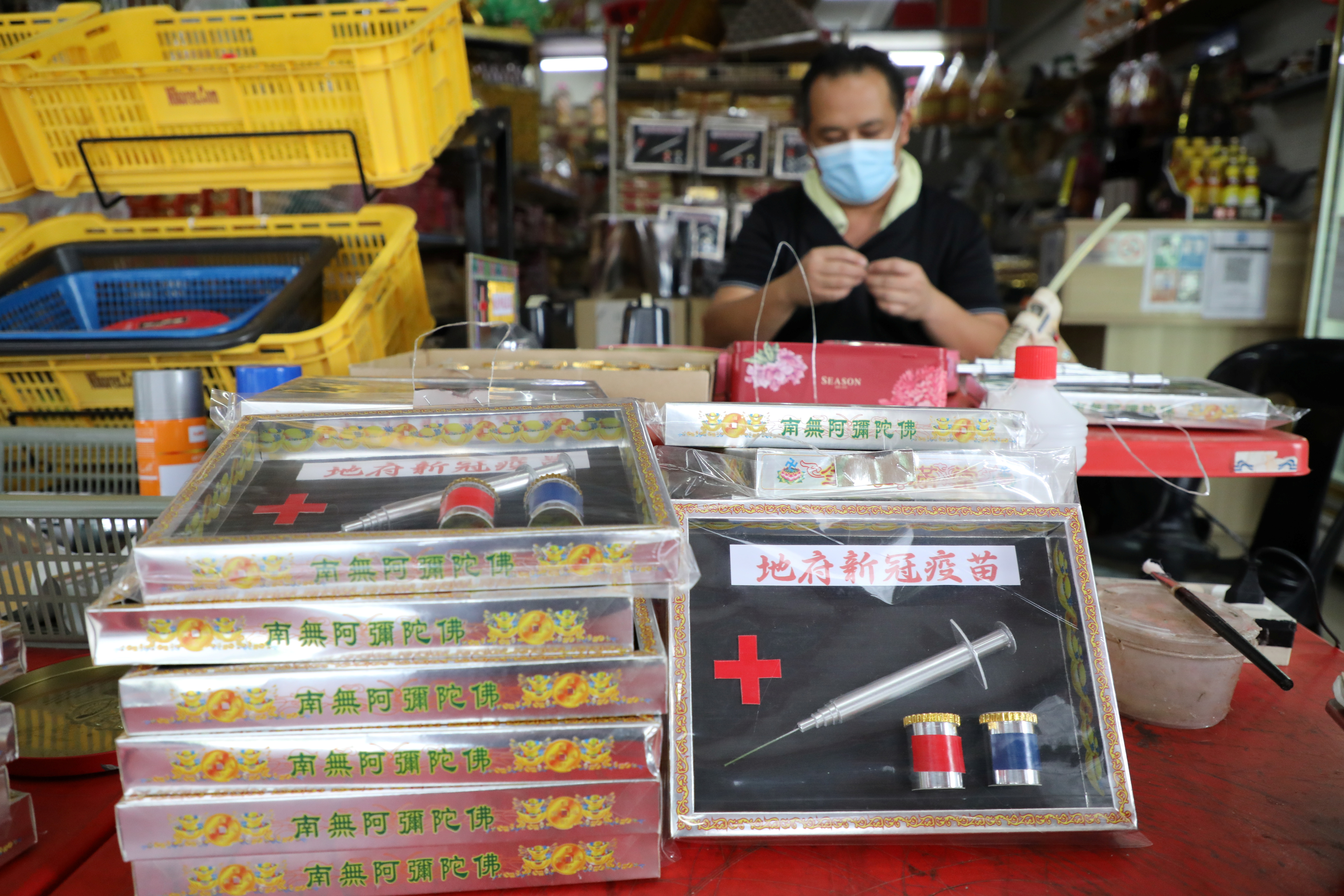 Prayer paraphernalia shop owner Raymond Shieh makes handmade paper vaccines at his shop in Johor Bahru