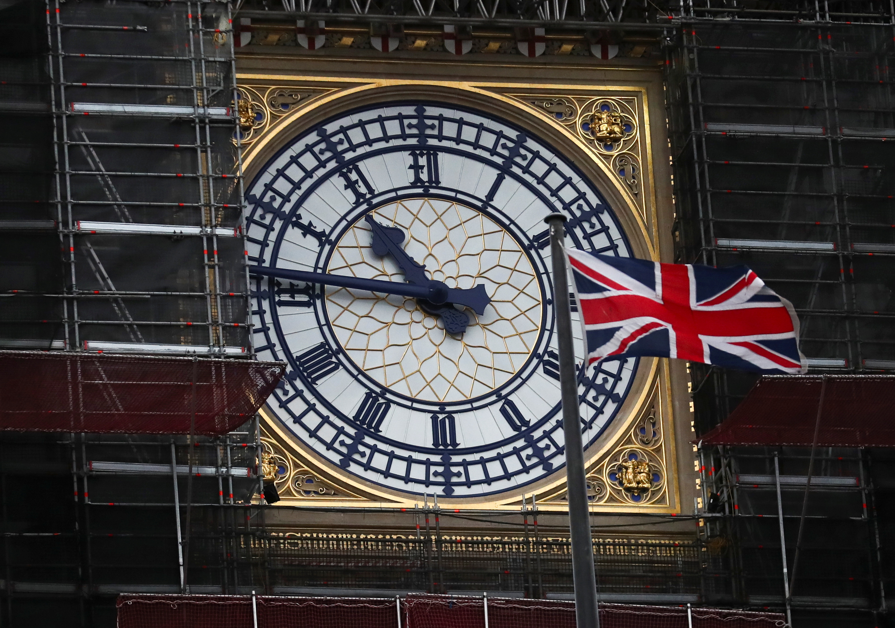 Union Jack flag flutters in front of Big Ben's clock face in London