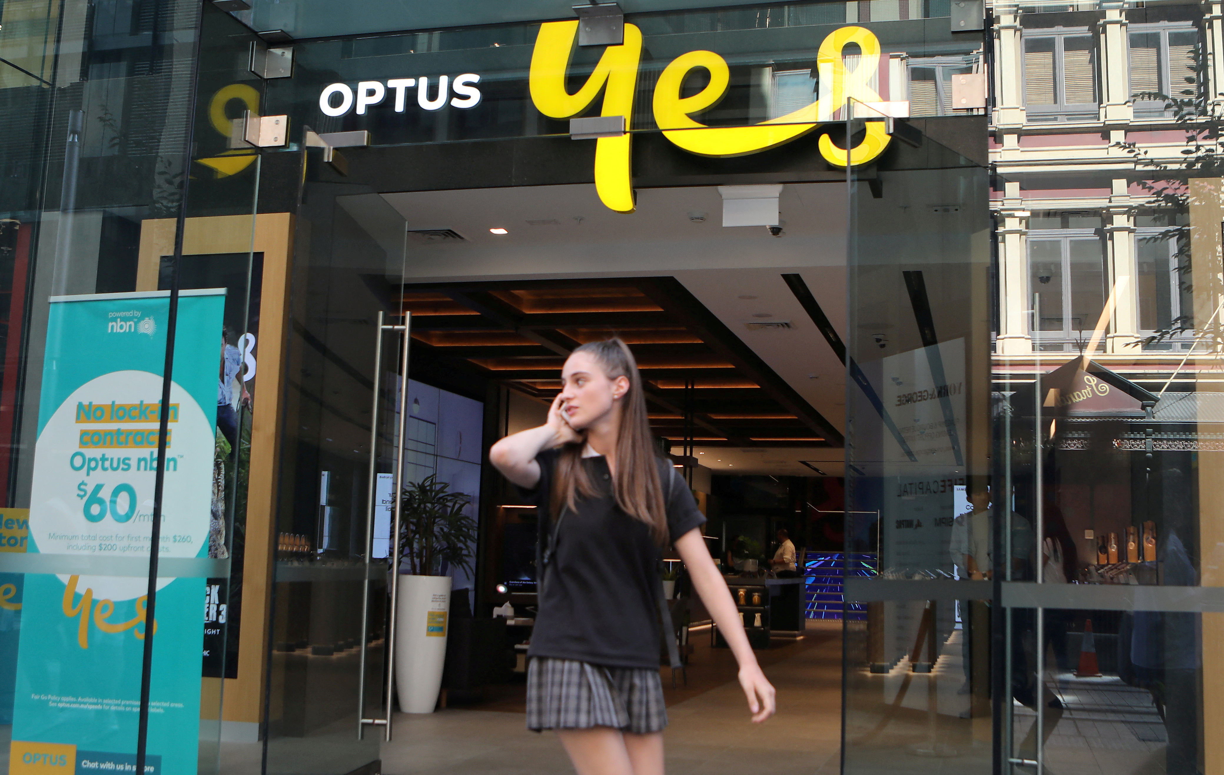 Một người phụ nữ sử dụng điện thoại di động khi đi ngang qua cửa hàng Optus ở Sydney