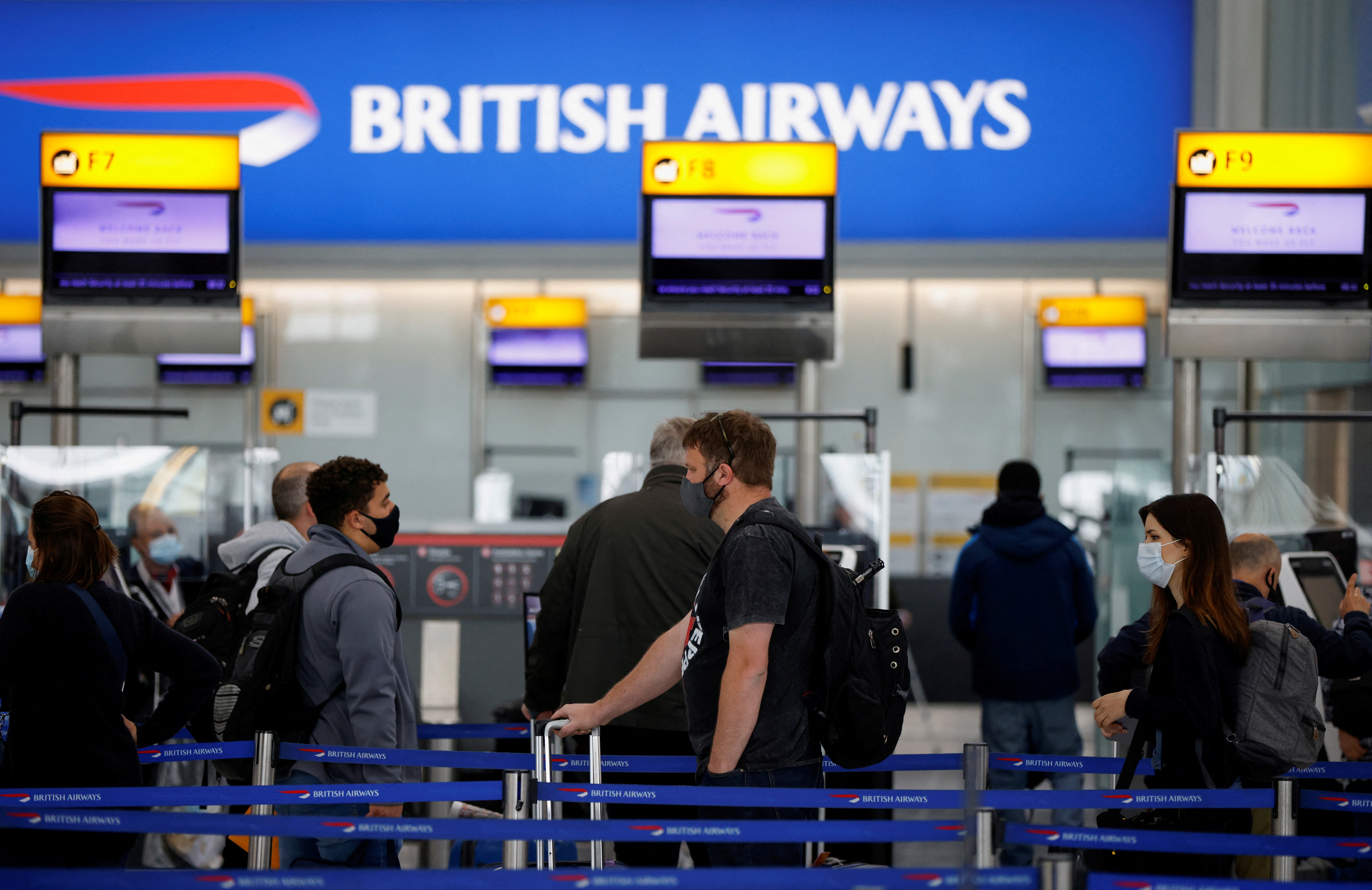 Passengers stand in a queue to the British Airways check-in desks at Heathrow Airport