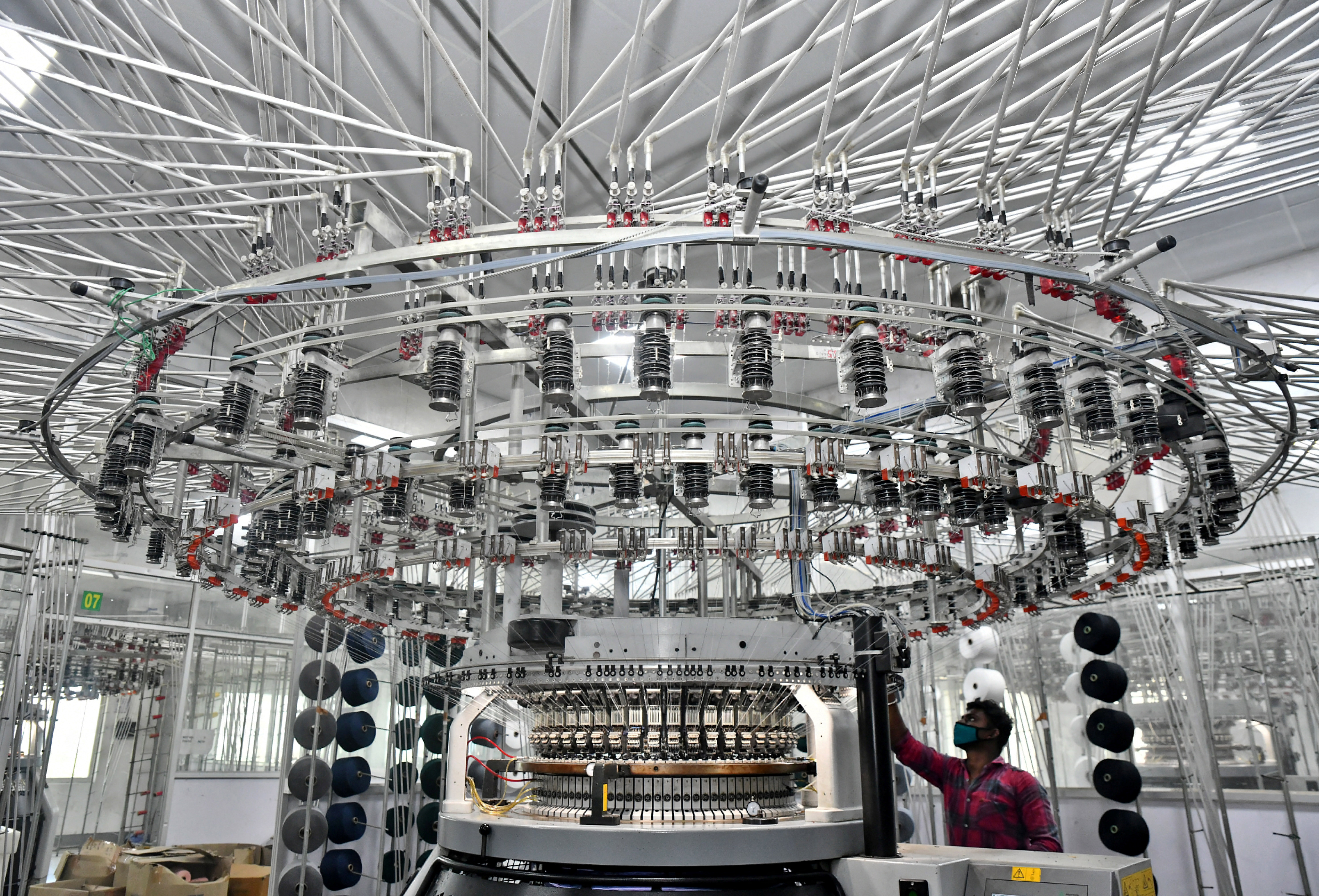 A worker operates a knitting machine at a textile factory of Texport Industries in Hindupur