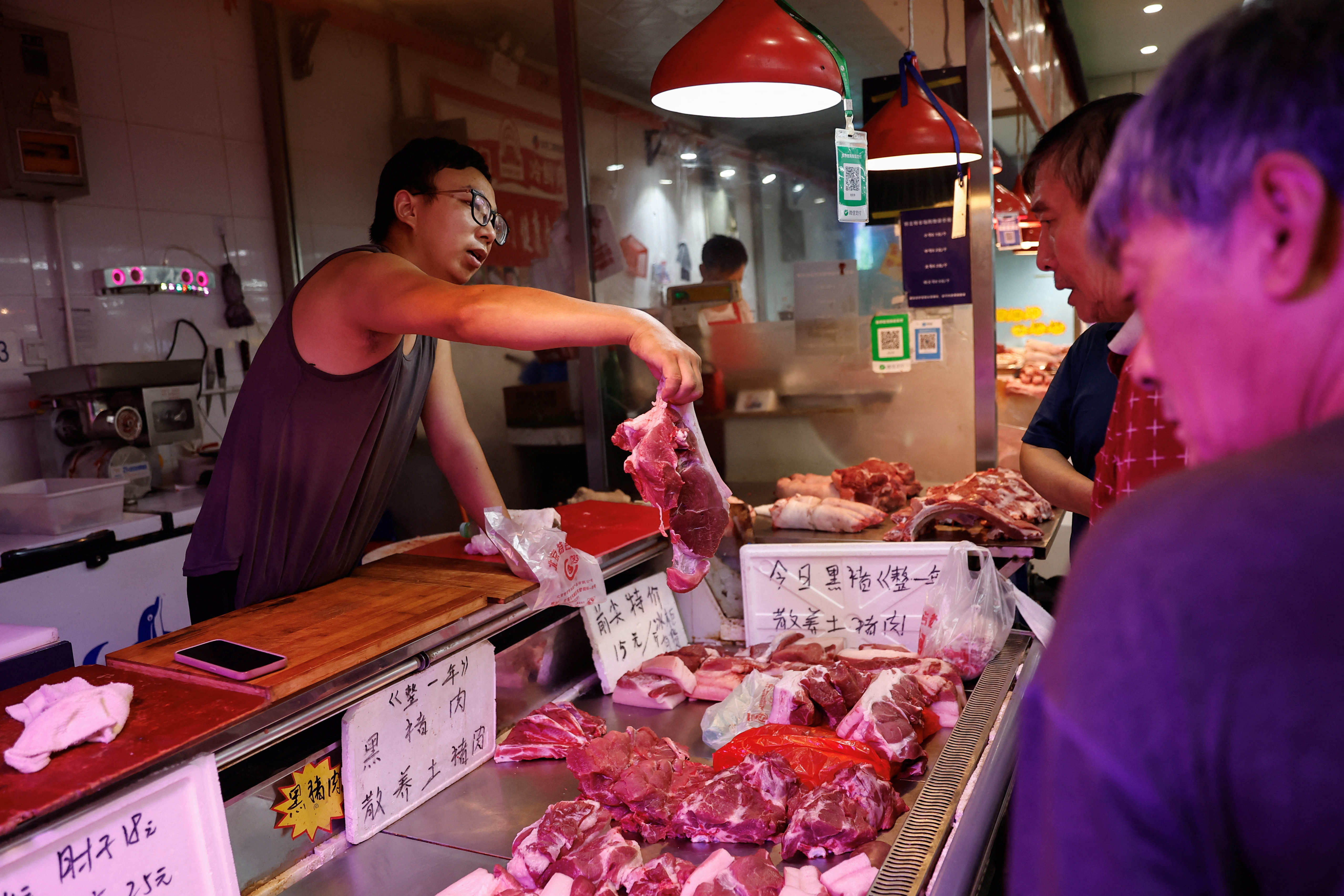 Pork vendor attends to a customer at a morning market in Beijing