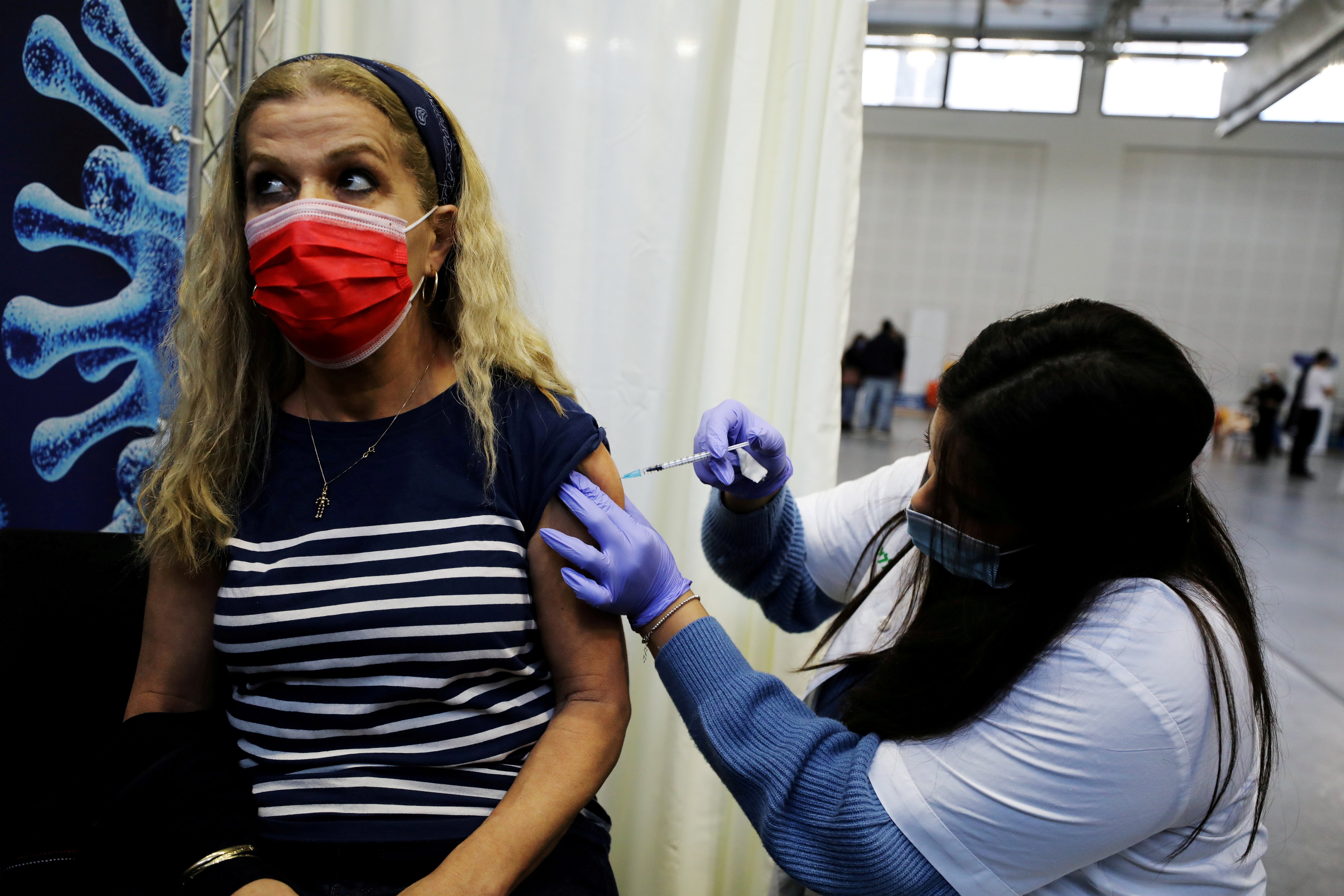 A woman receives a vaccination against the coronavirus disease (COVID-19) at a temporary Clalit healthcare maintenance organisation (HMO) centre, at a basketball court in Petah Tikva