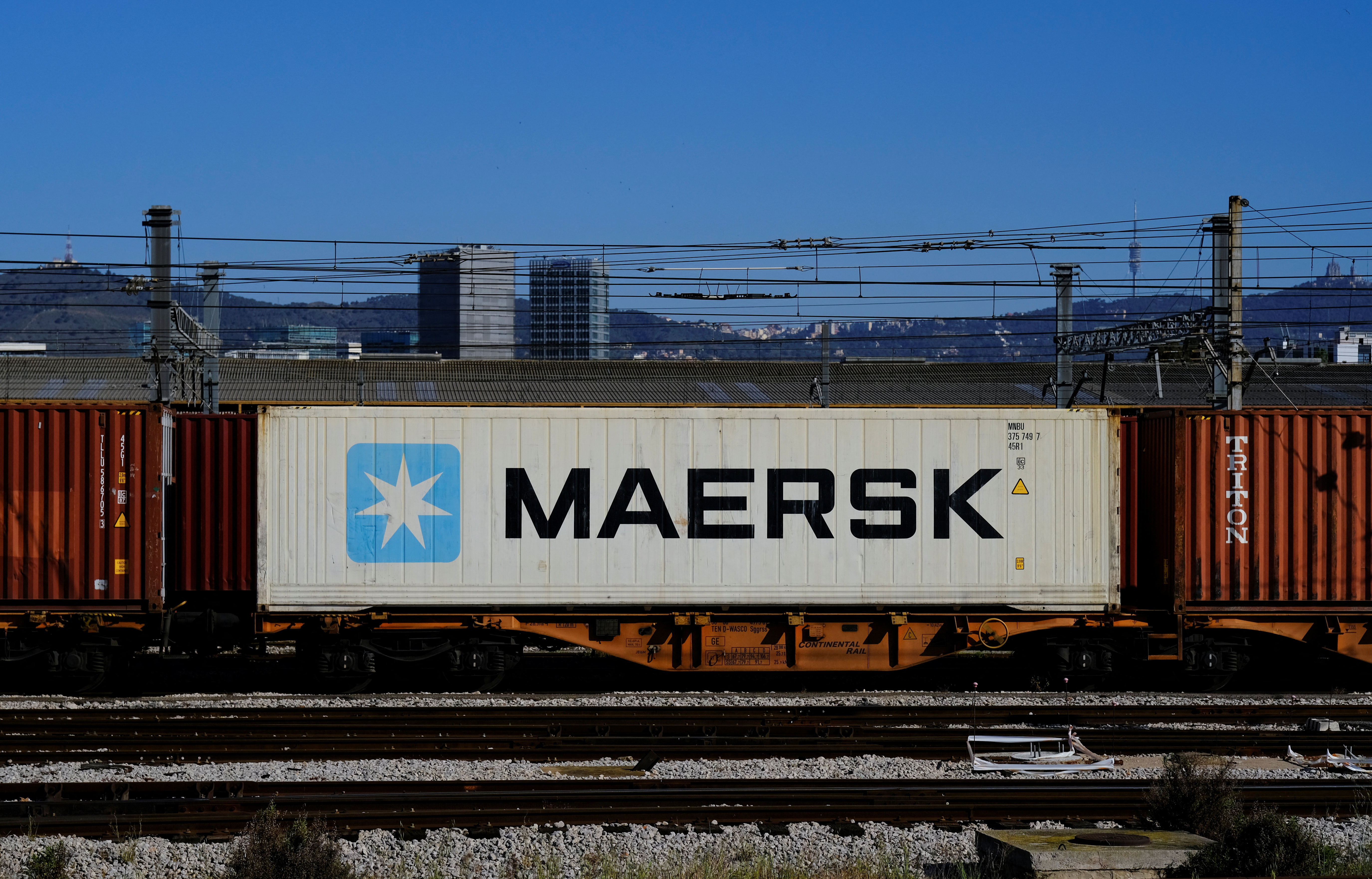 Maersk container is transported by a train near a port of Barcelona